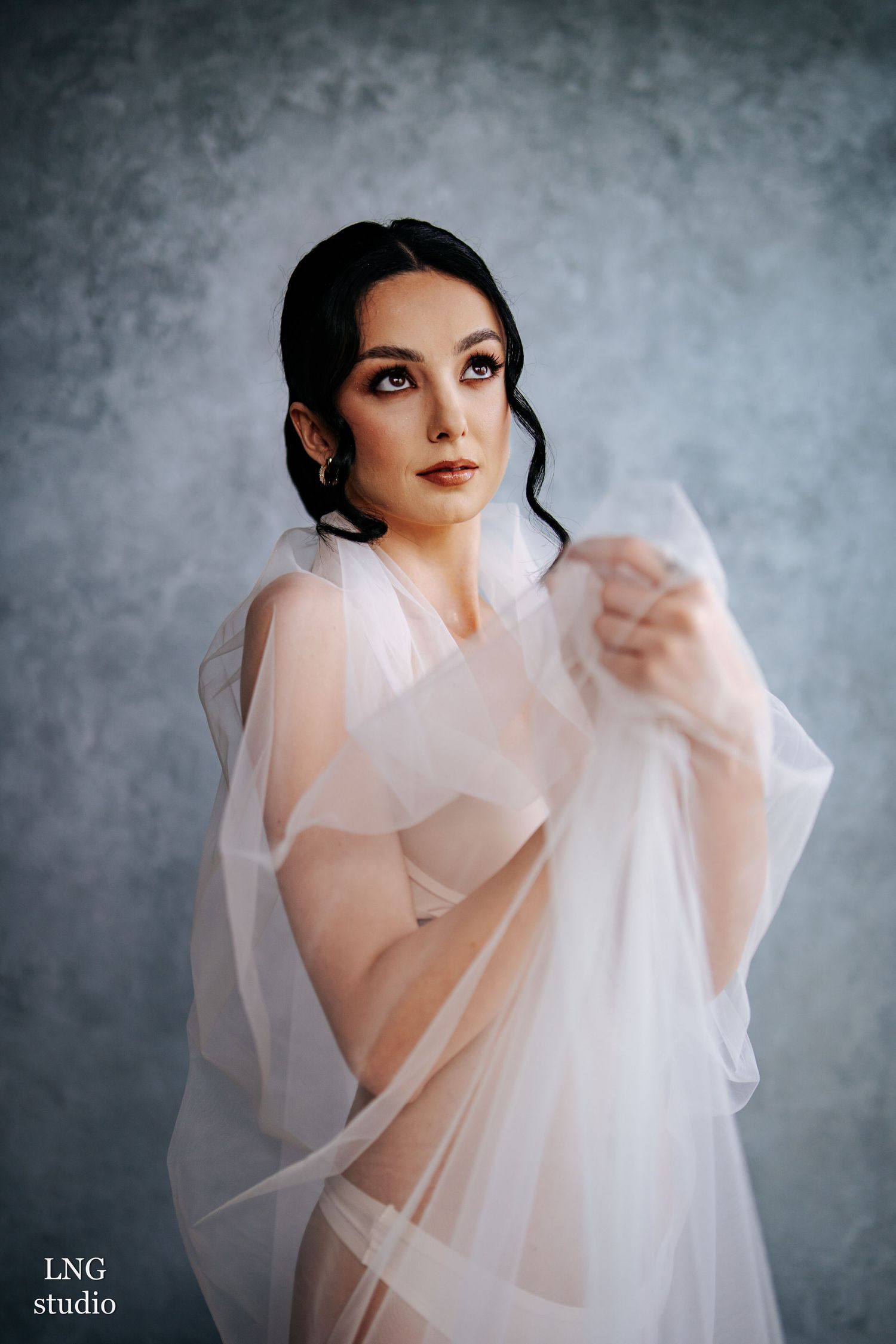 A figure in ethereal white tulle fabric creates an artistic fashion portrait series against a misty gray backdrop.