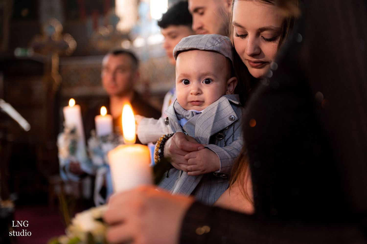 Candlelit Orthodox baptism ceremony in traditional church setting.