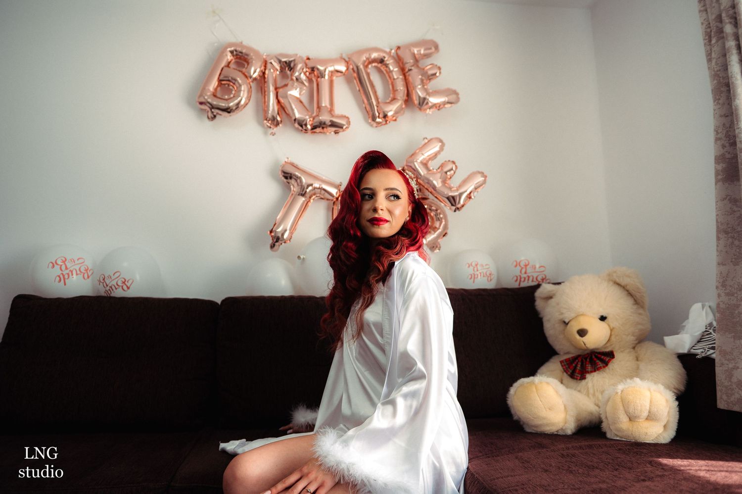 Bridal preparation scene with rose gold balloon decor and white robe.
