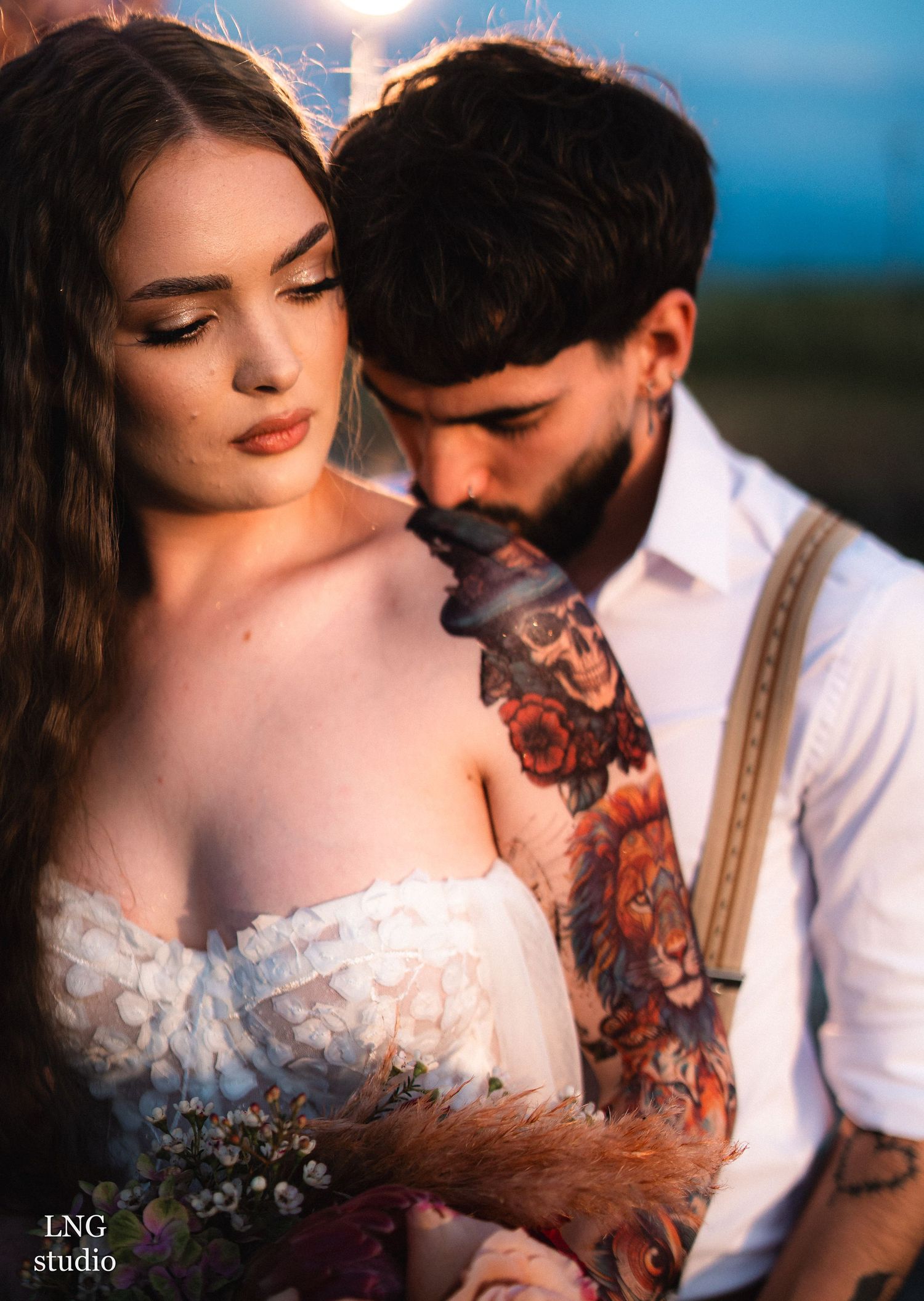 An engaged couple in wedding attire embraces during a sunset photo shoot with romantic lighting and natural scenery.