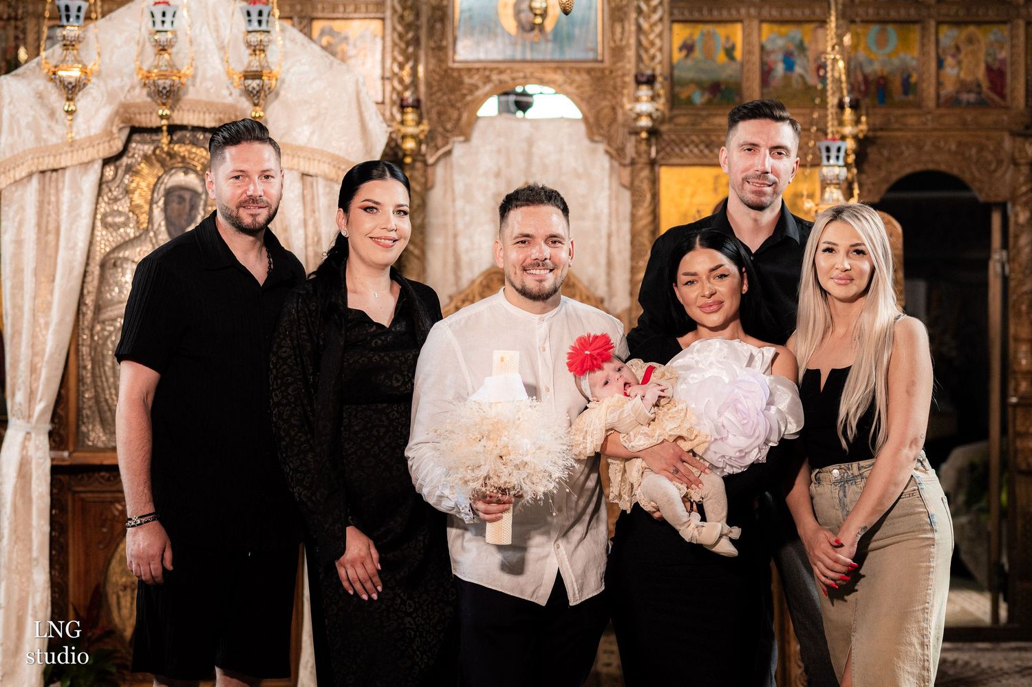 Group celebration photo in front of ornate Orthodox church iconography and golden decor.