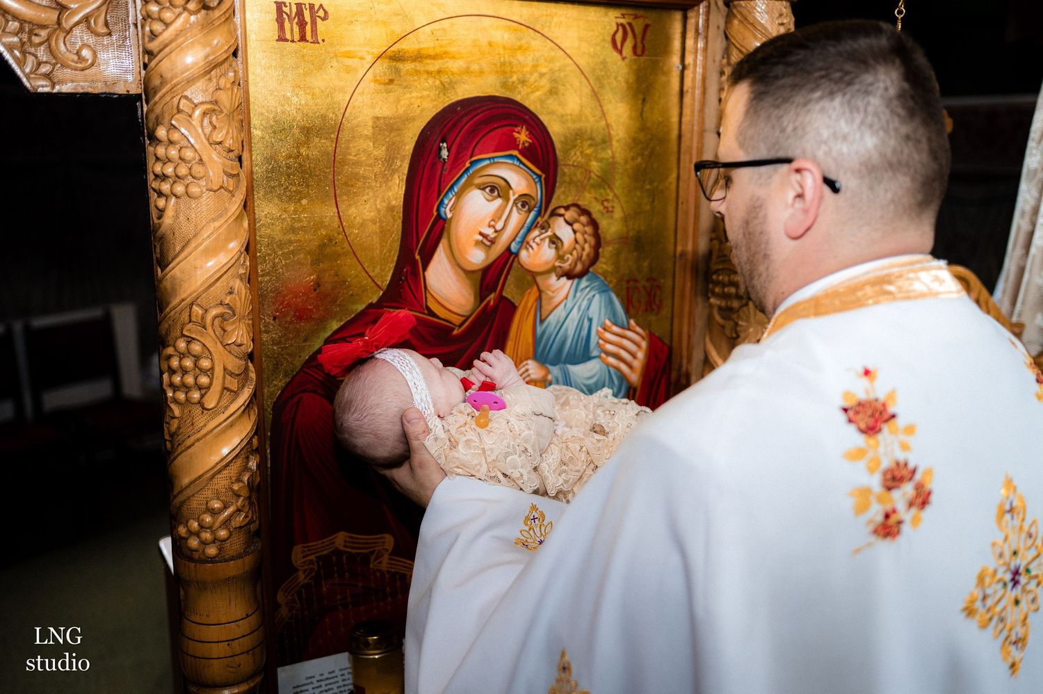 Religious icons and ornate decorations adorn the walls of an Orthodox Christian church during a ceremony.