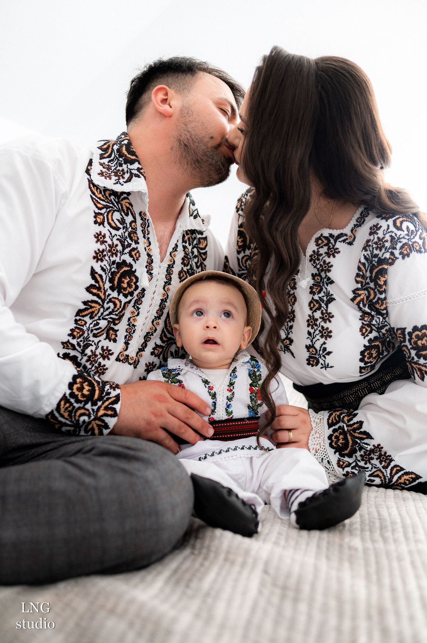 Intimate family portrait wearing matching white vyshyvanka shirts with ornate embroidery designs.