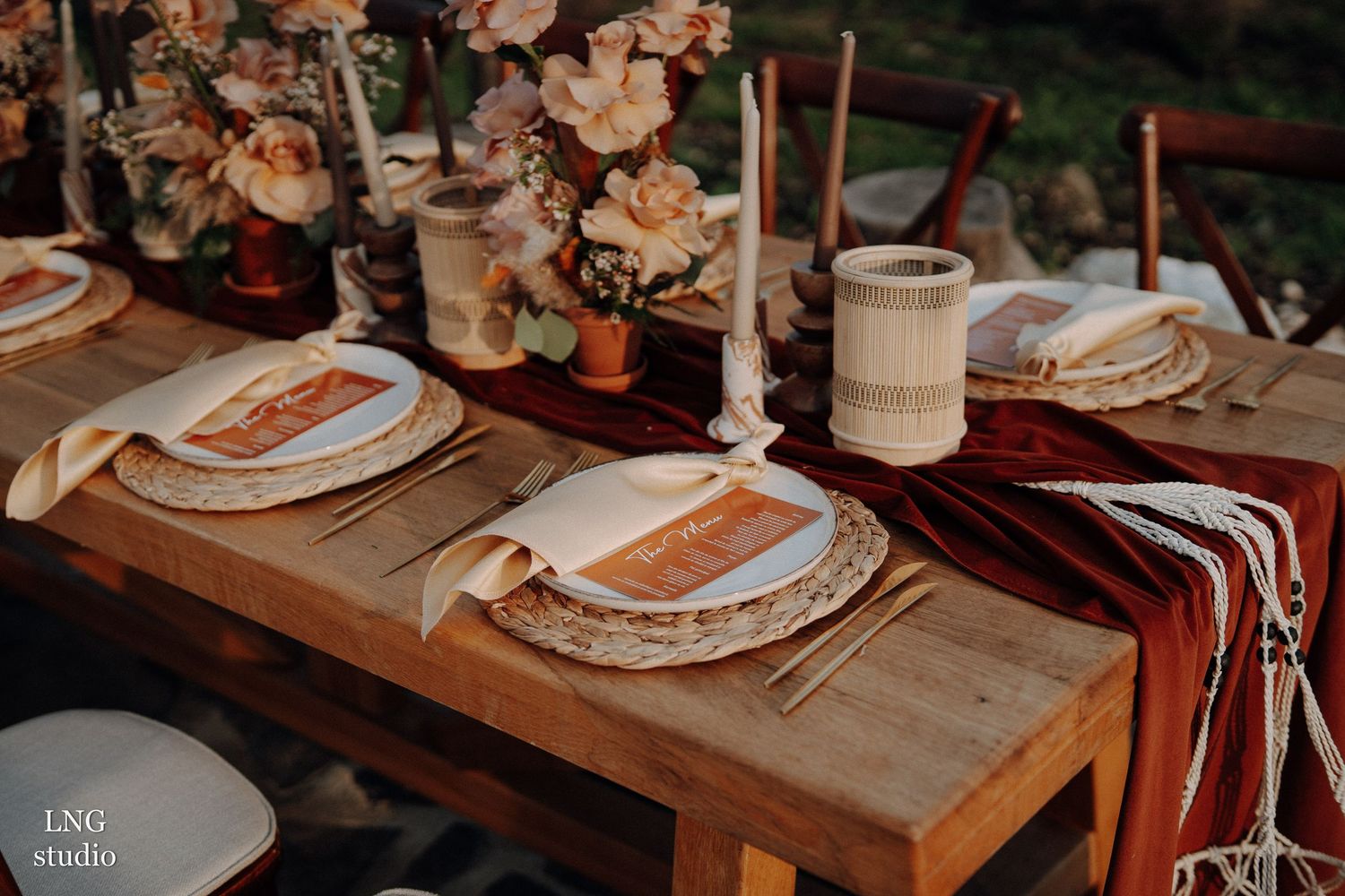 Rustic table settings with white plates and moody lighting create an intimate wedding reception atmosphere.