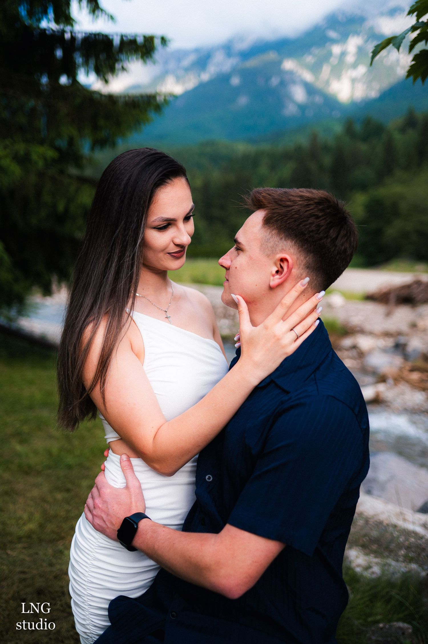 A romantic portrait of a couple with dramatic mountain scenery behind them.
