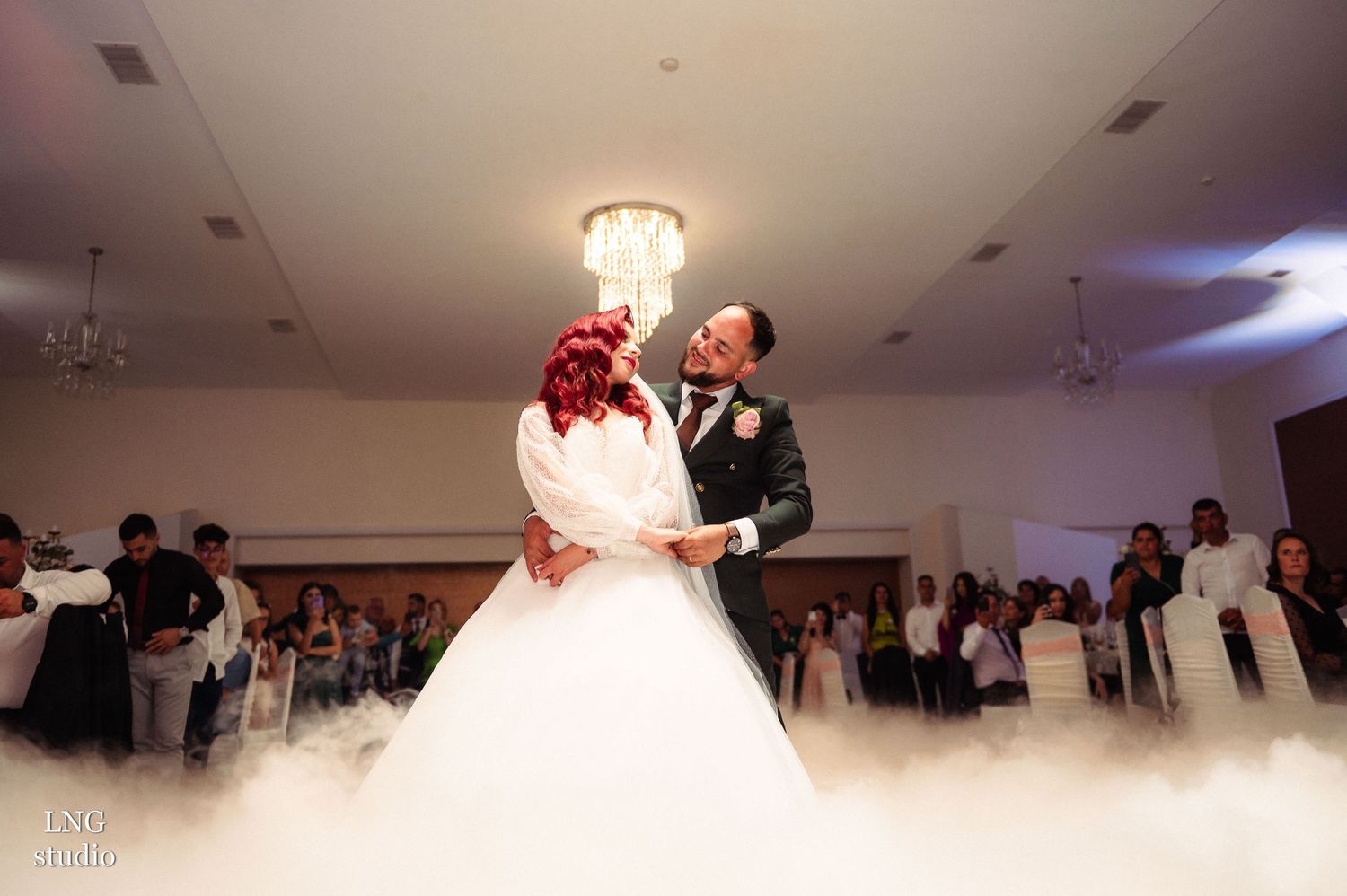 Wedding couple dancing surrounded by fog effects on ballroom dance floor.