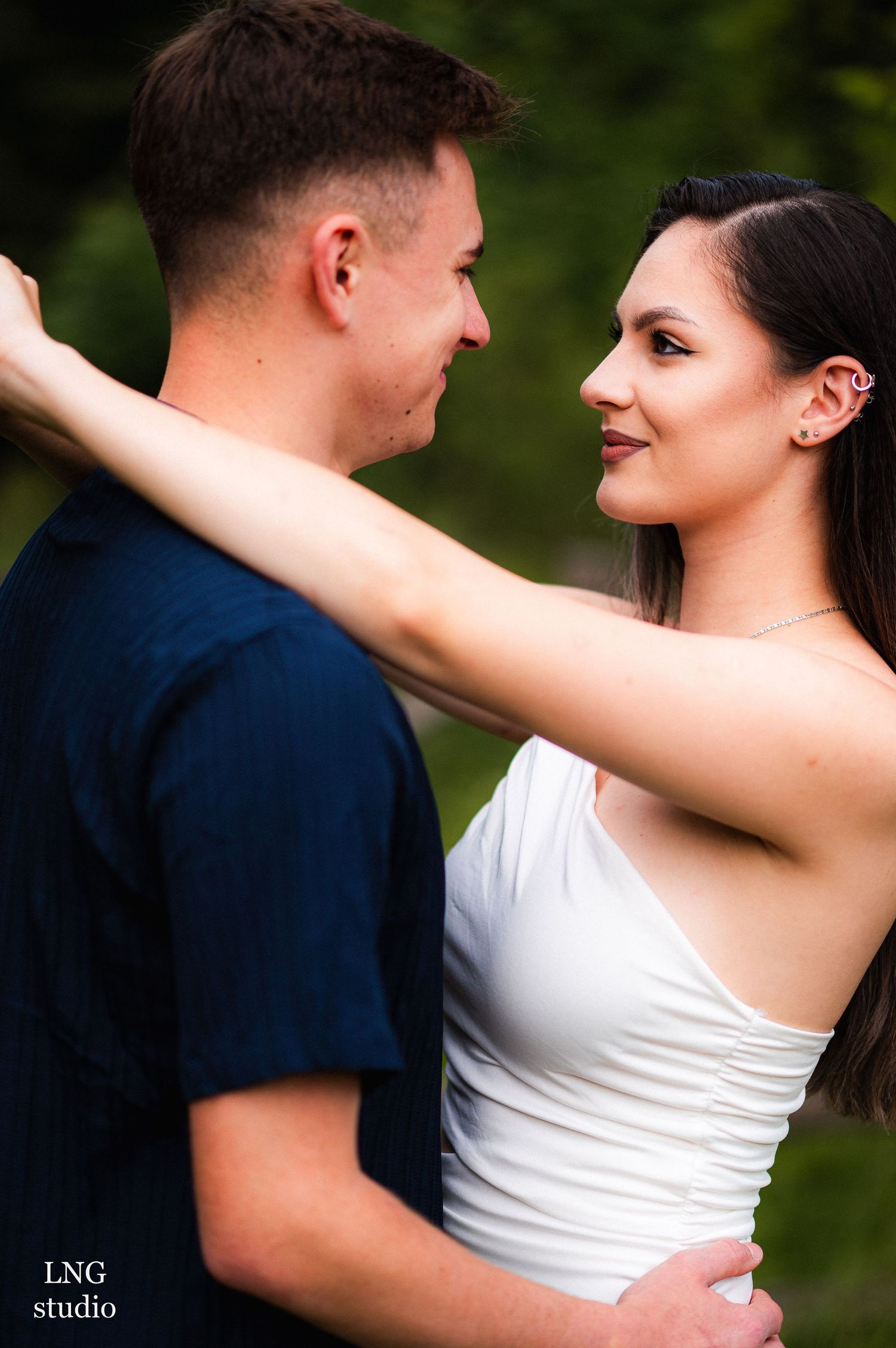 A couple in casual attire shares an intimate embrace outdoors.