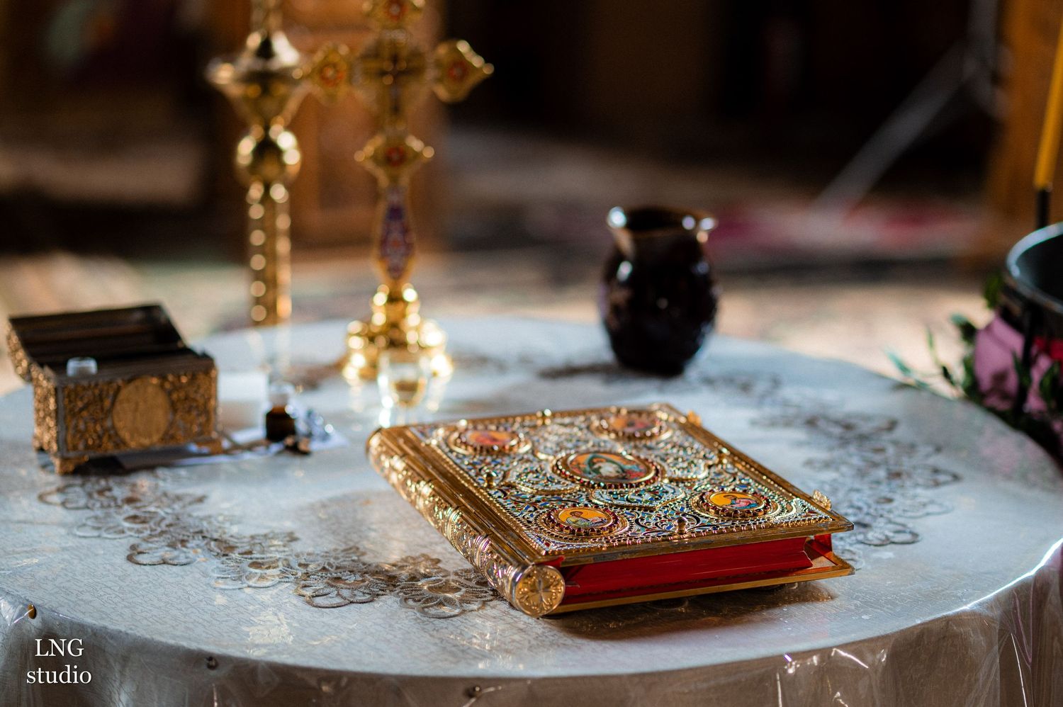 Ornate religious book with golden decorations and ceremonial items on a white tablecloth.