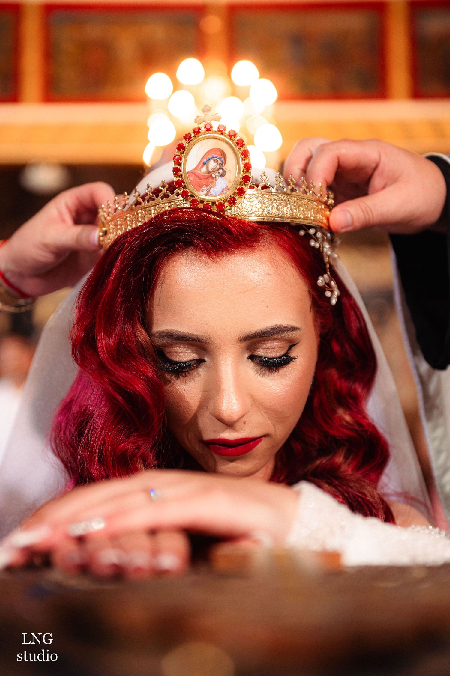 Close-up of illuminated crown on bride with red hair and dramatic makeup.