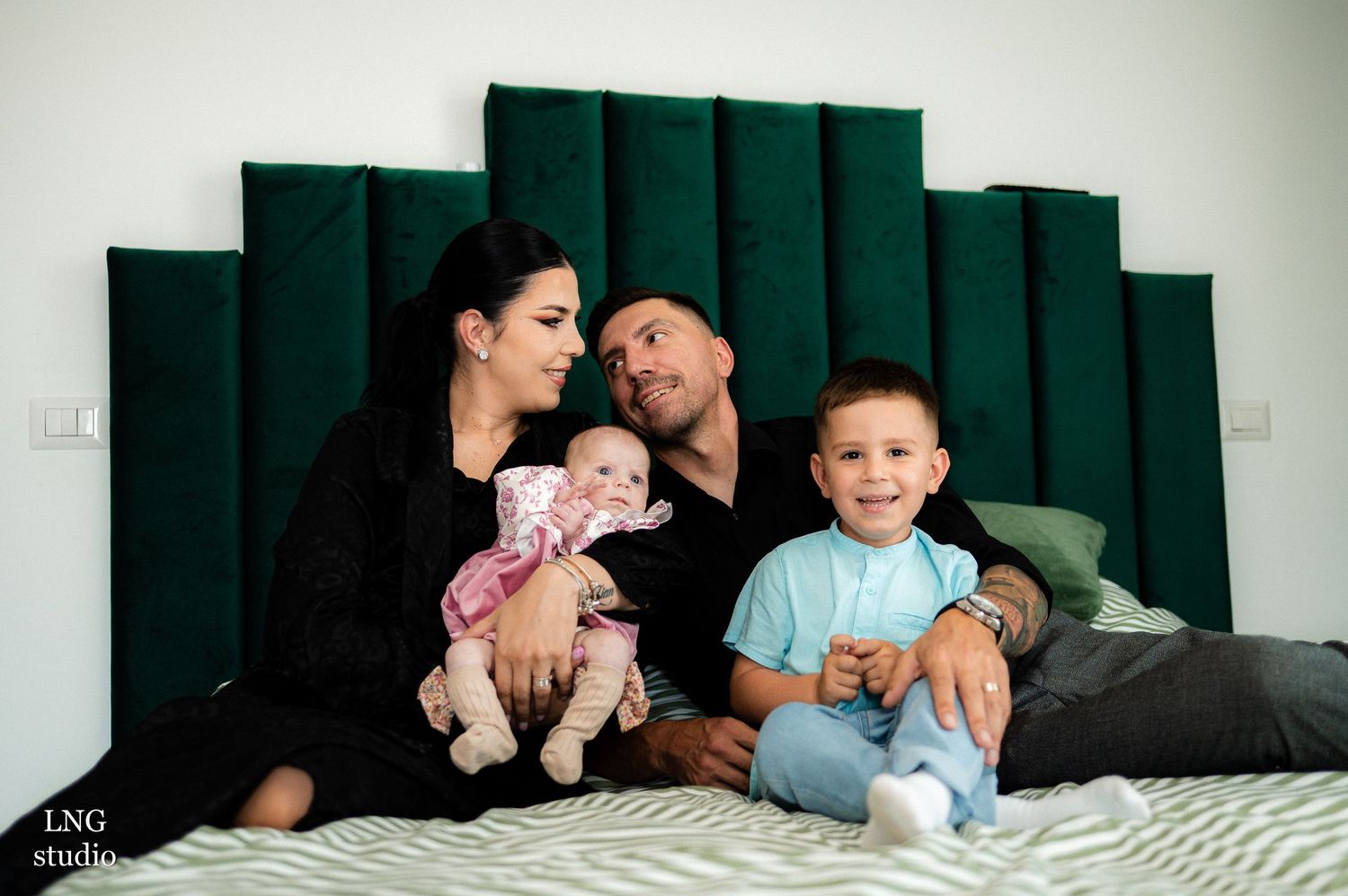 Family poses together on bed in black and white tones for intimate lifestyle portraits.