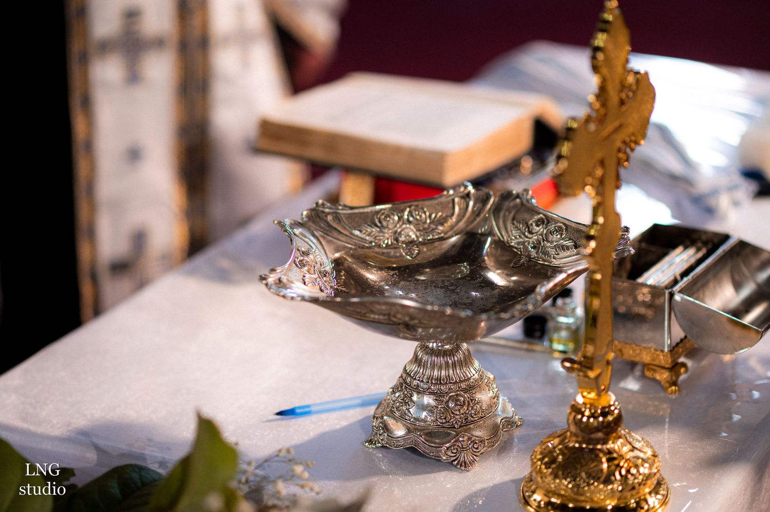 Close-up of ceremonial silver and gold objects on white altar cloth.