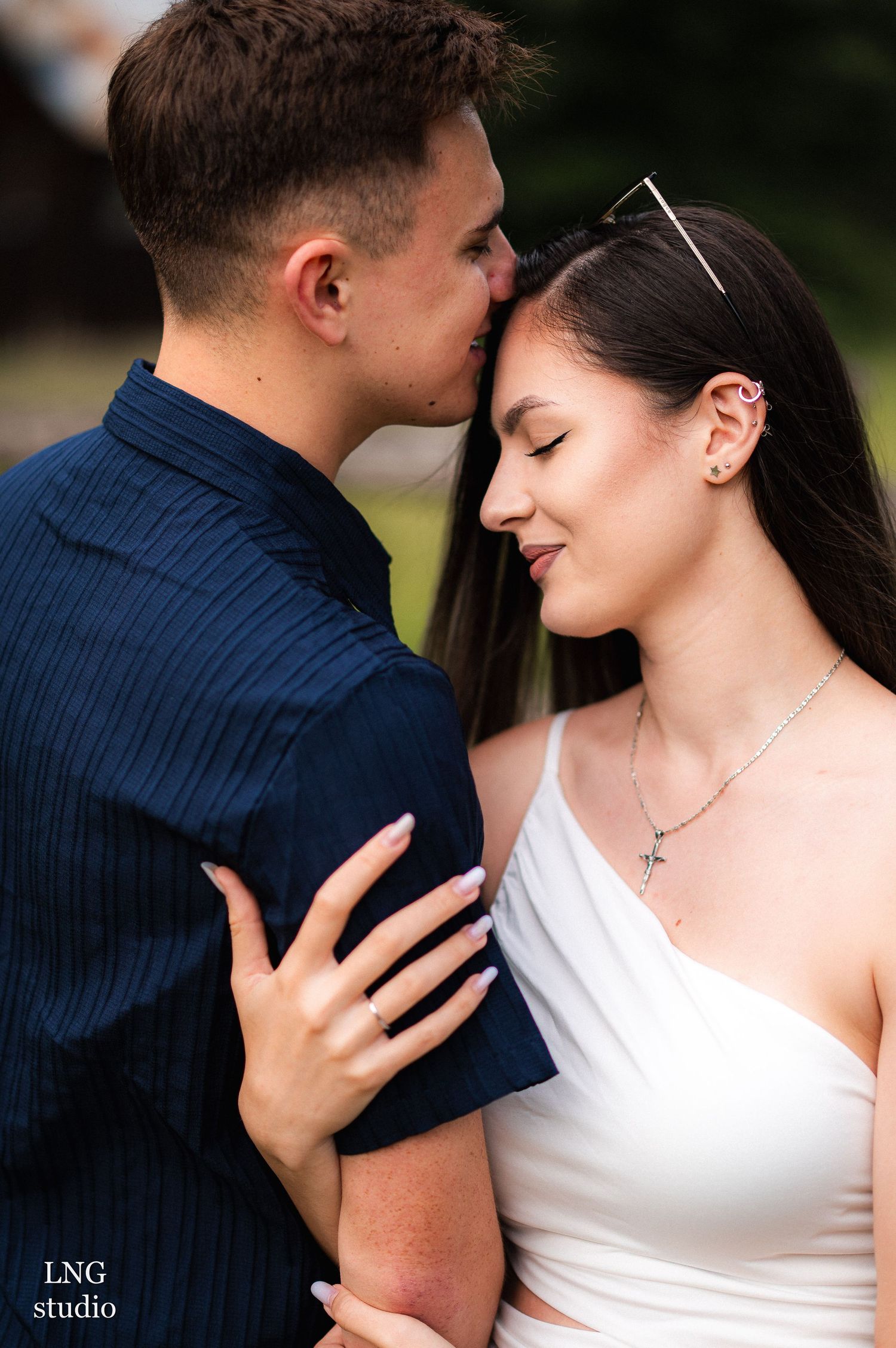 Tender close-up moments between couple in white and navy outfits with studio watermark.