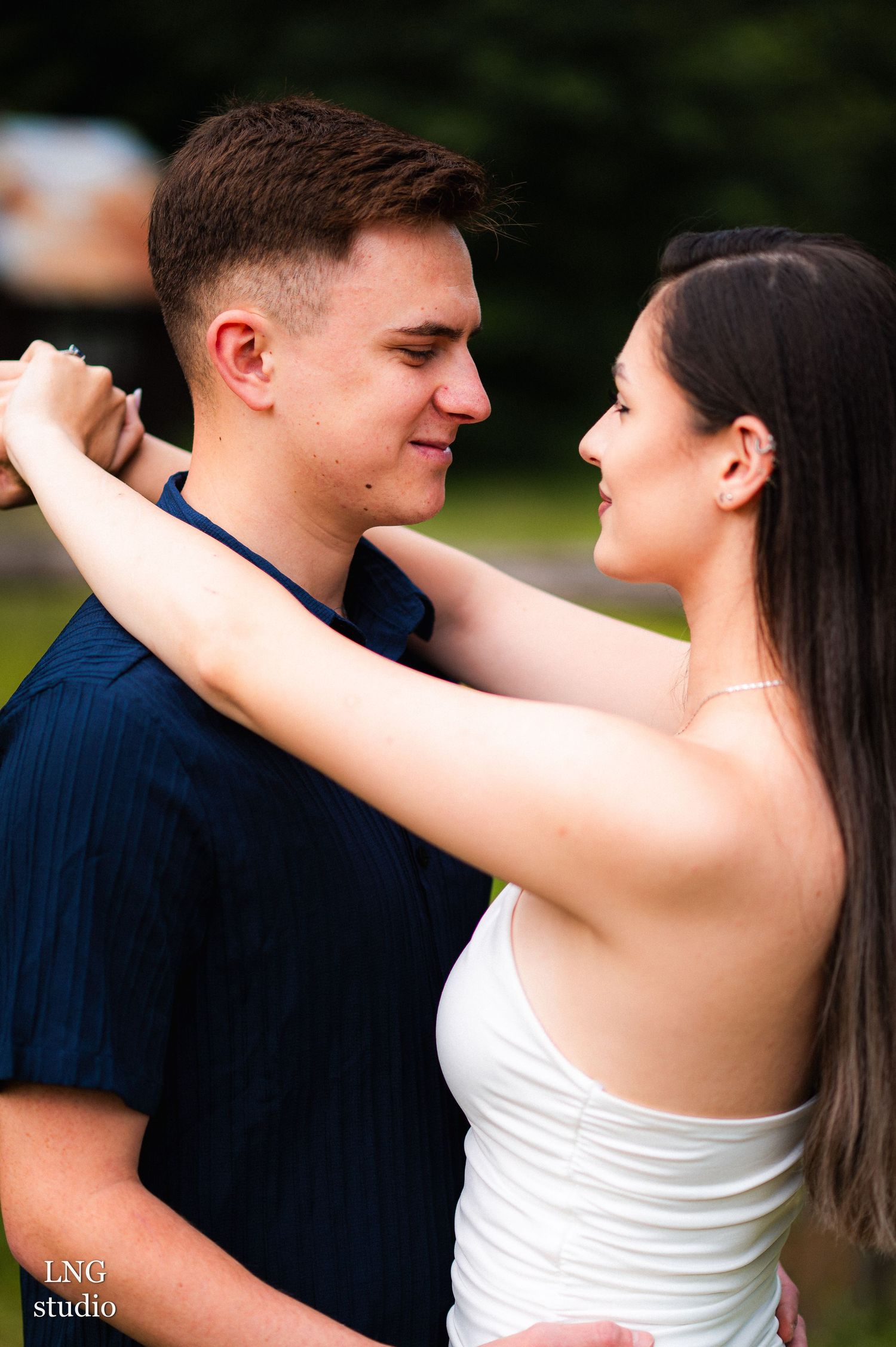 Couple shares romantic embrace against natural outdoor backdrop.