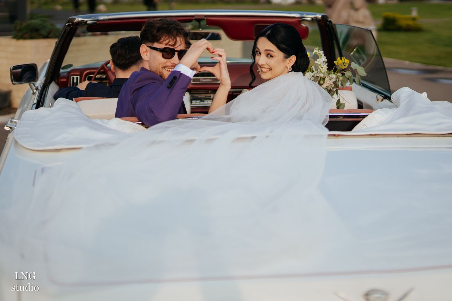 Wedding reception guests at decorated dining tables celebrate and enjoy conversations with drinks outdoors.