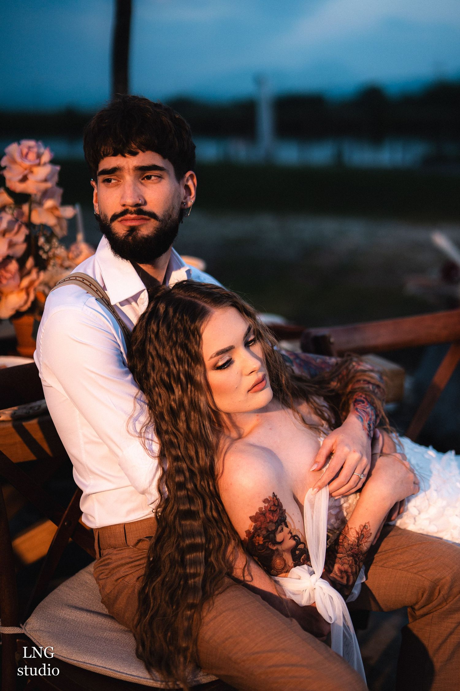 Intimate wedding couple embracing on a rustic wooden deck during golden hour with soft lighting.