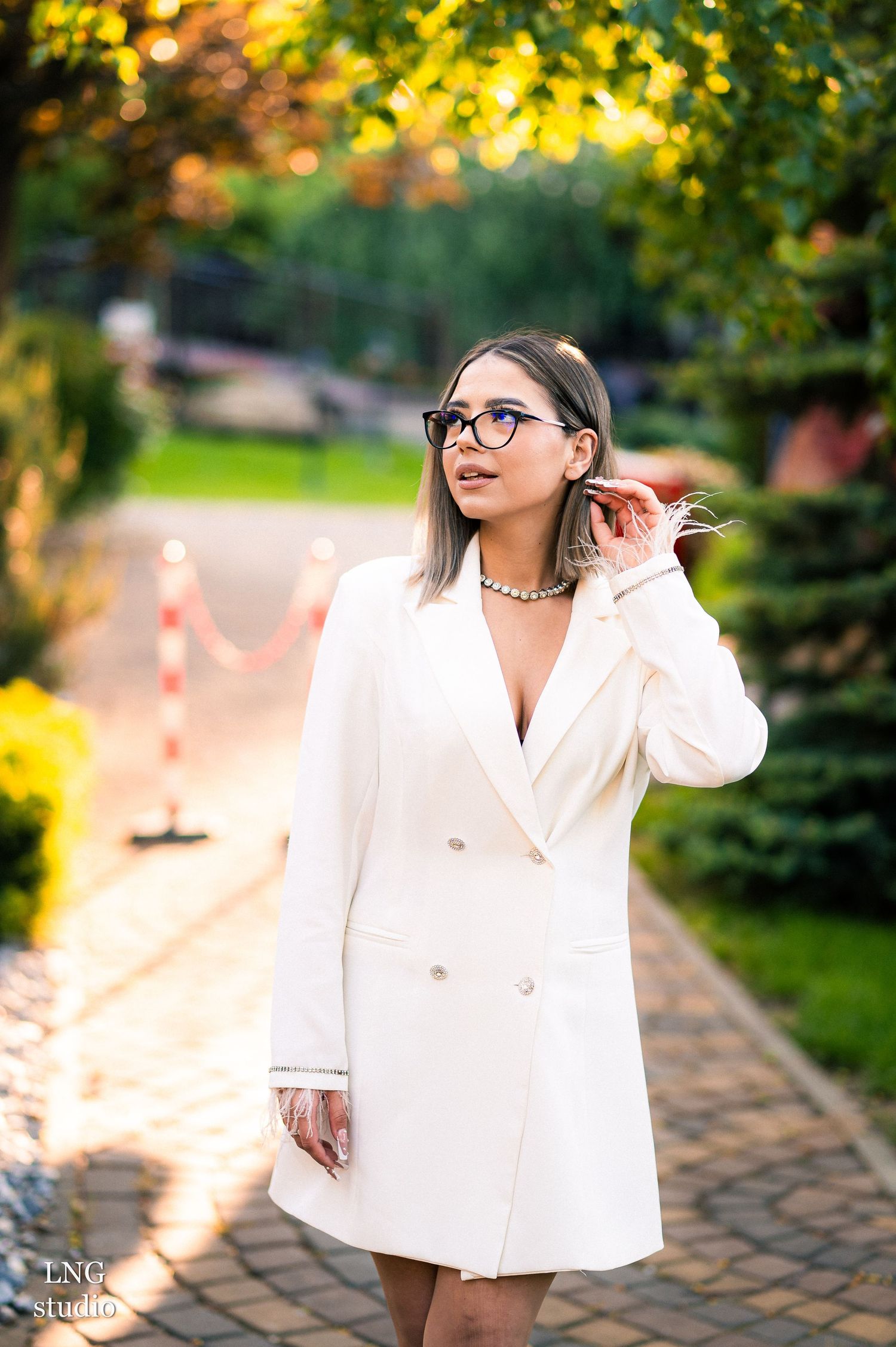 Stylish outdoor photoshoot featuring white blazer against autumn foliage.