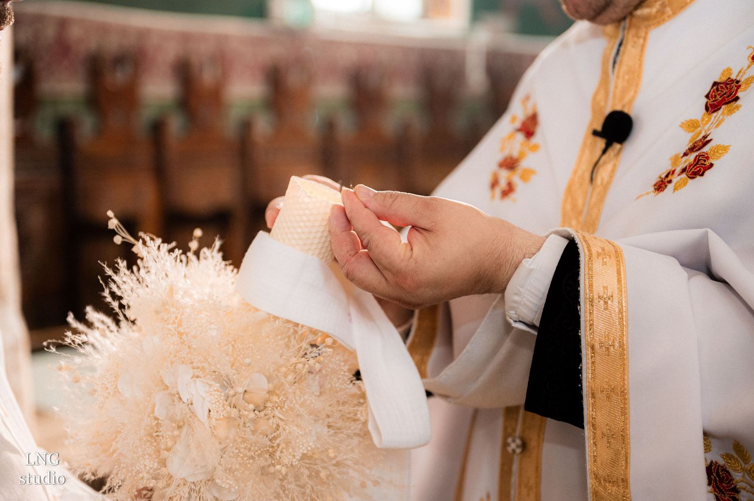 Close-up of white baptismal robes with golden religious embroidery during ceremony.