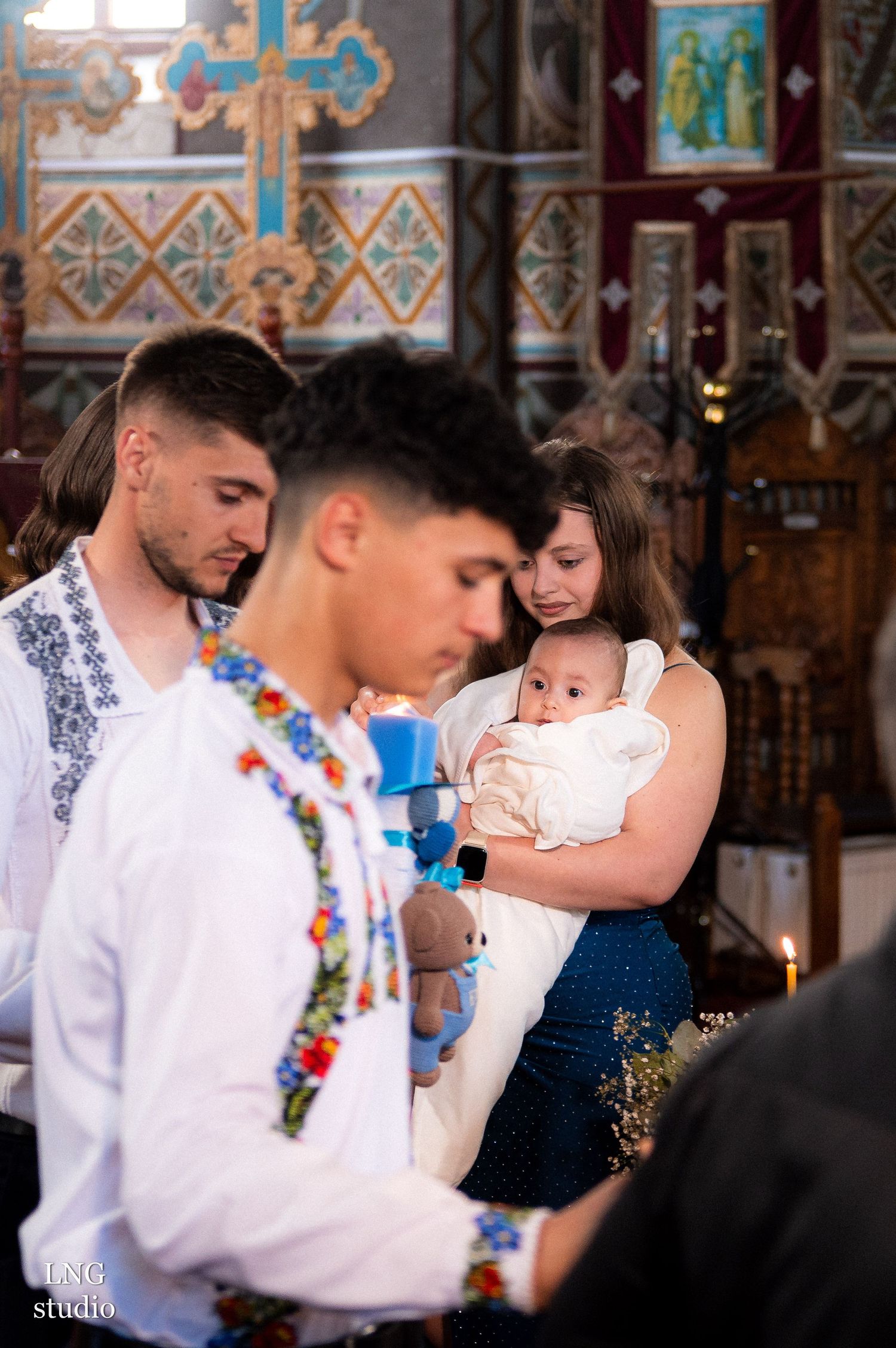 Traditional Orthodox baptism ceremony with participants wearing embroidered white clothing.