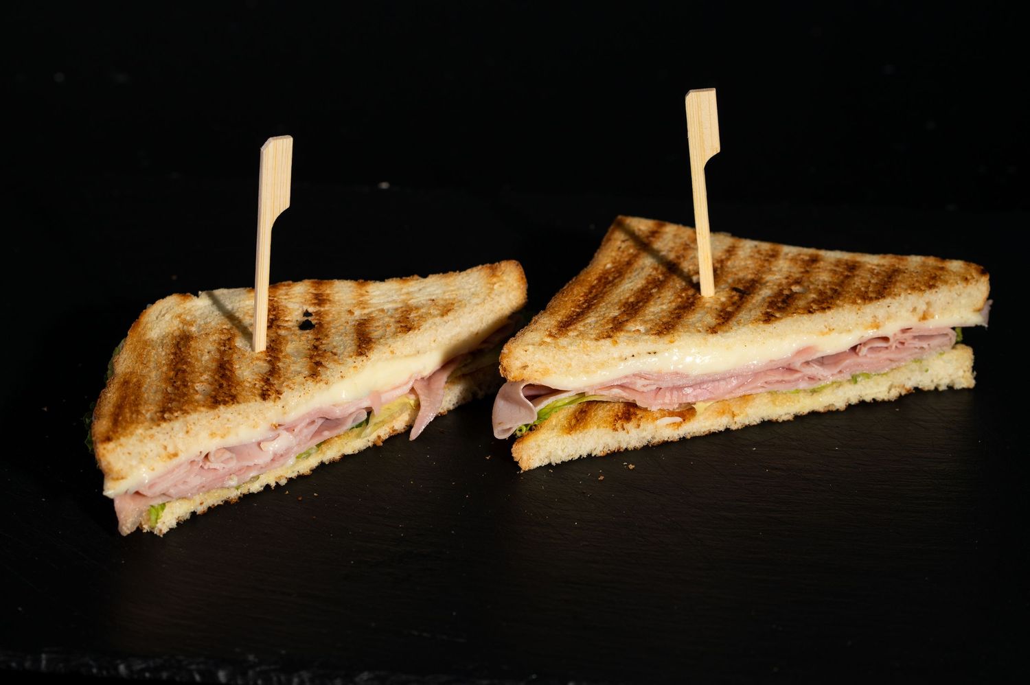 Grilled panini sandwich with ham and cheese shown in progressive slicing sequence.
