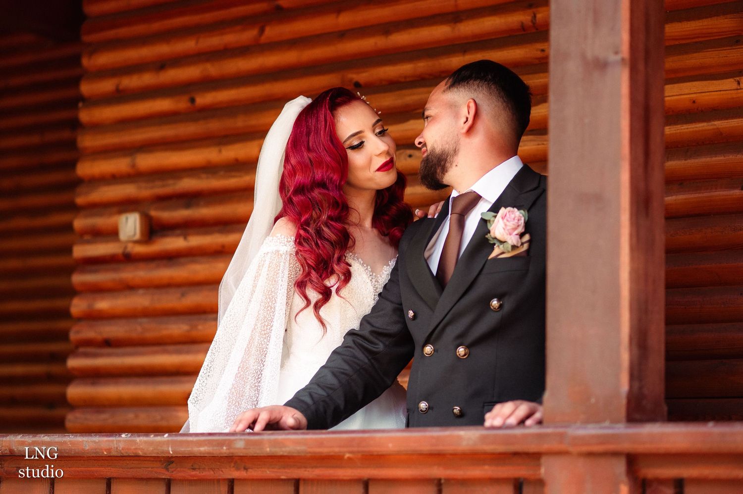 Romantic moments captured between newlyweds in front of wooden cabin walls.