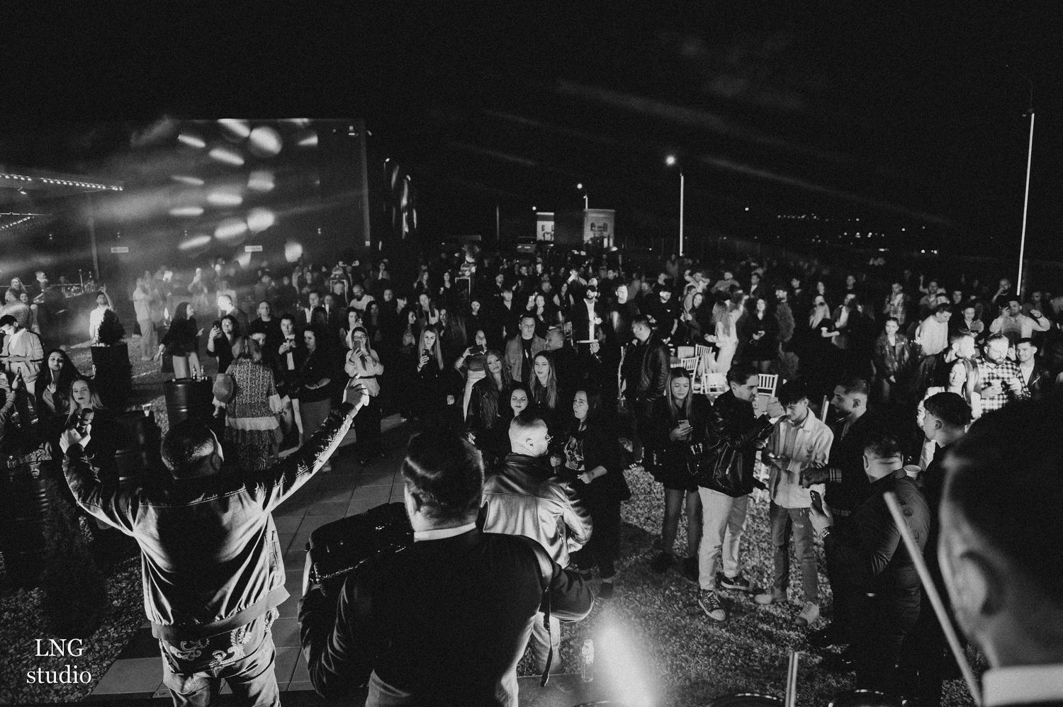 Concert venue crowd shown in black and white with dramatic lighting.