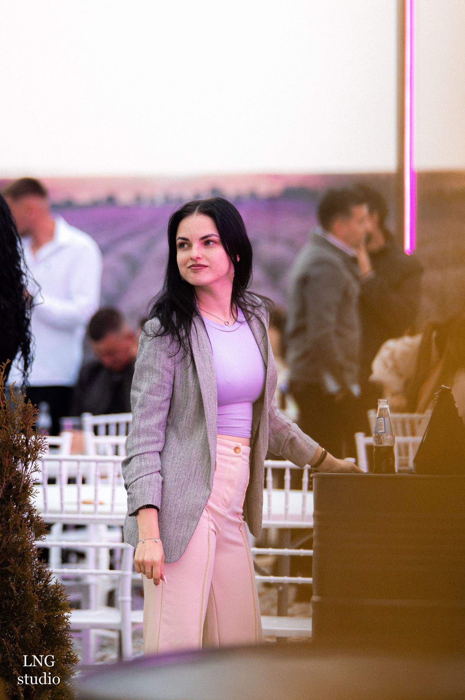 Elegant event space with white chairs and pink sunset lighting.