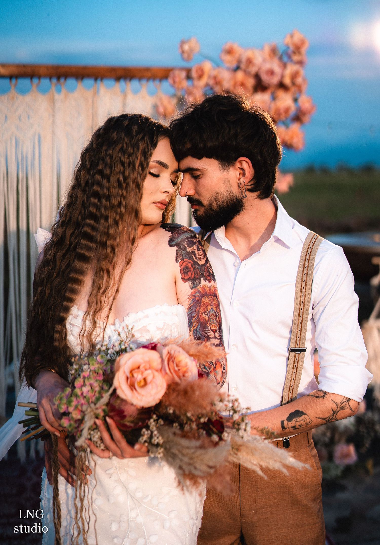 Romantic sunset wedding photo showing couple in intimate moment with peachy roses and rustic decor.