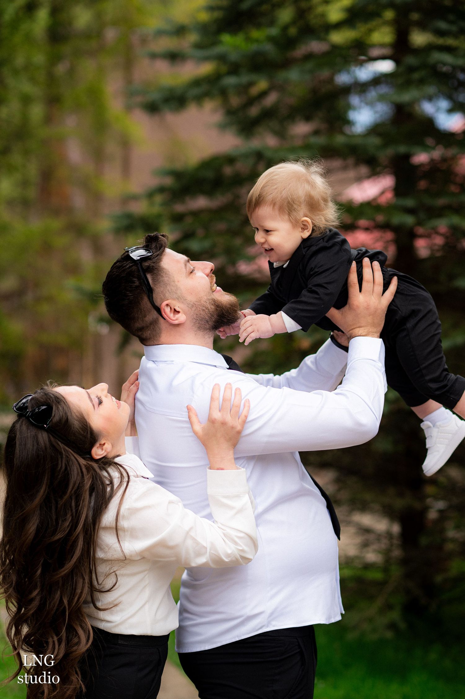 Candid family photo showing playful interaction and laughter in an outdoor setting.