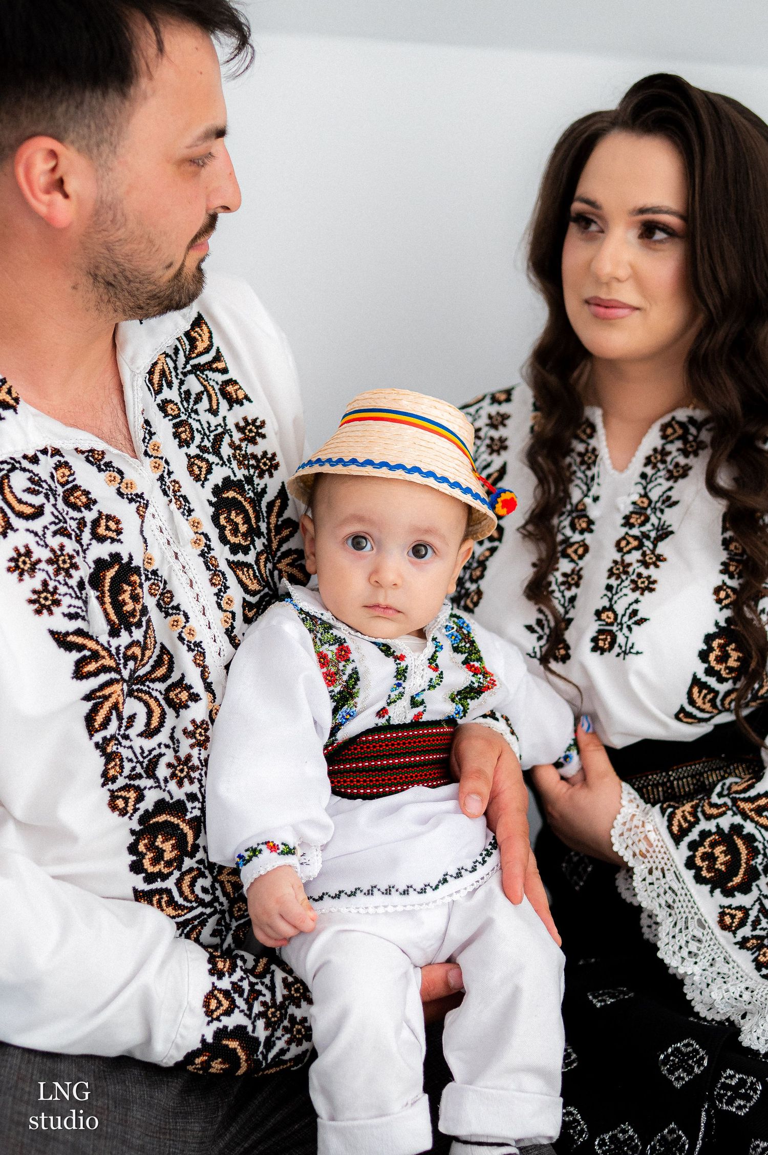 Family wearing traditional Ukrainian embroidered vyshyvanka outfits in white with intricate brown floral patterns.