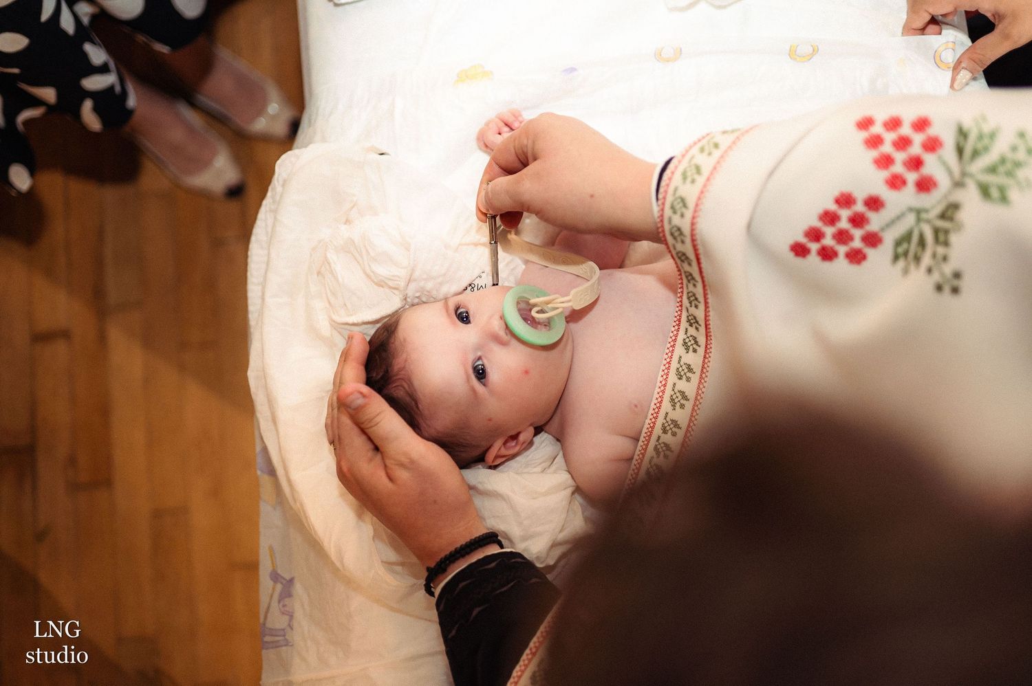 Baby wearing white clothing during baptism ceremony.