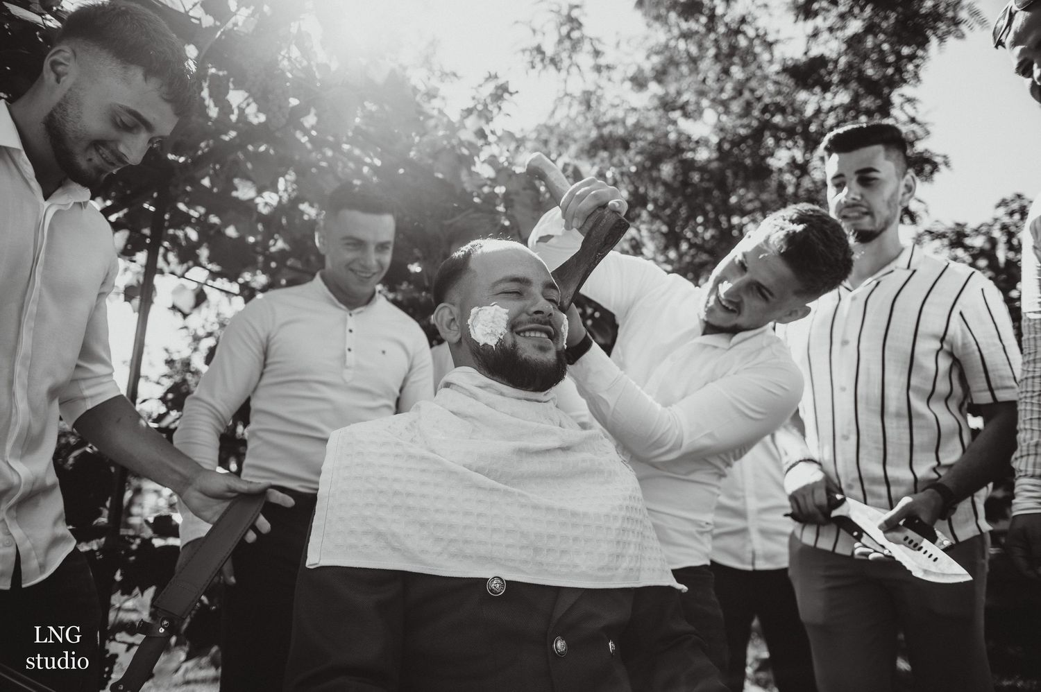 Black and white photo of groomsmen sharing laughs during pre-wedding preparations.