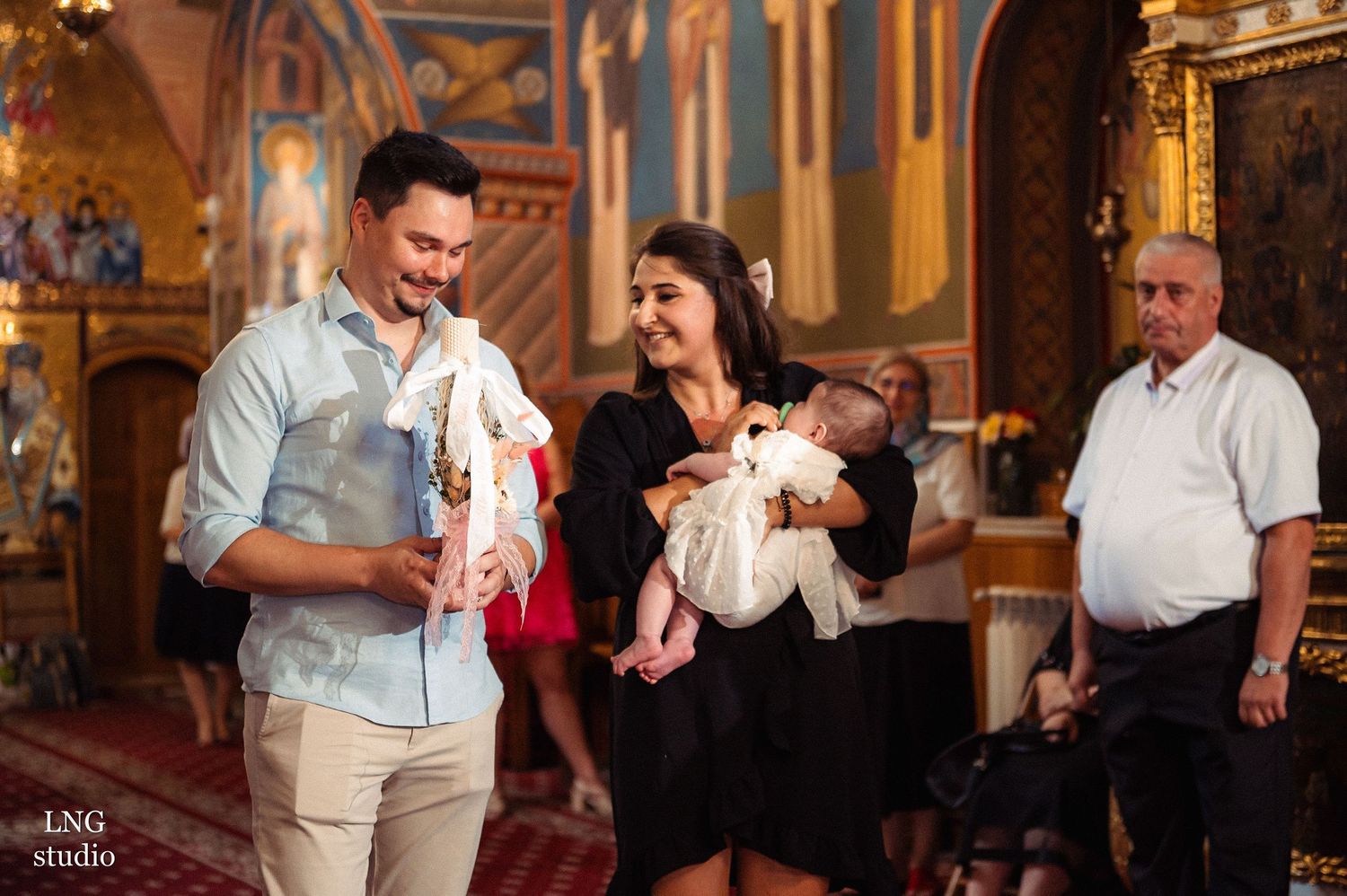 A joyful baptism celebration inside an ornate church with gilded decorations.