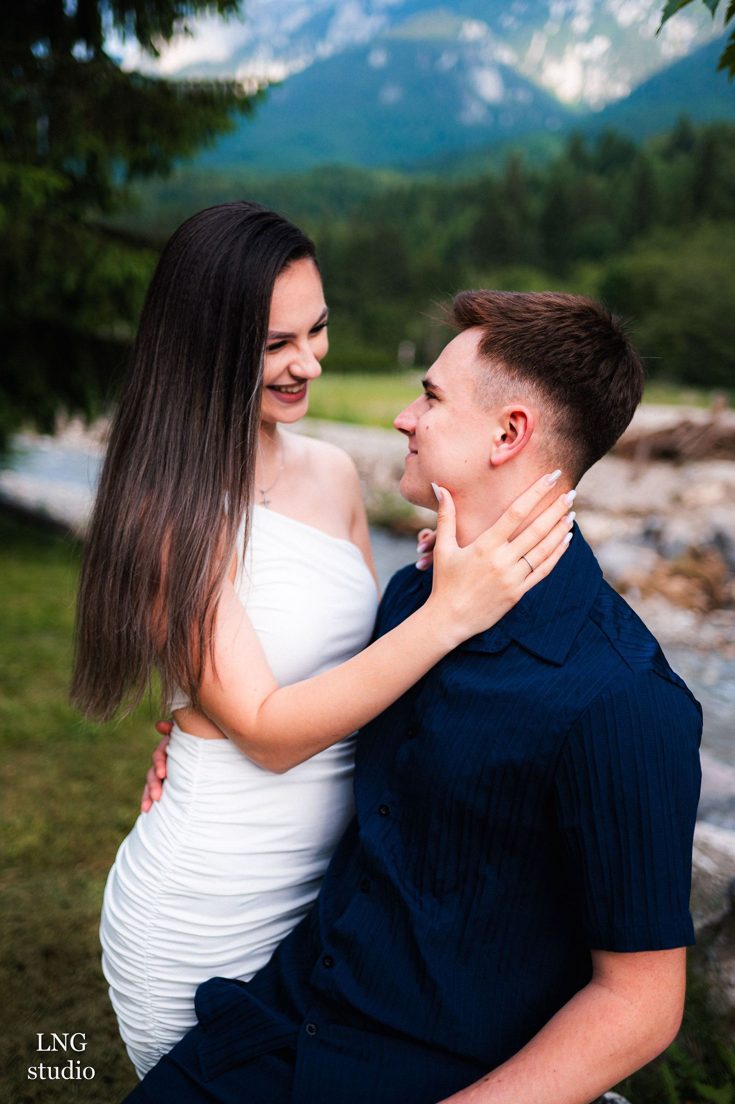 A tender moment between a couple in white and navy against mountain backdrop.