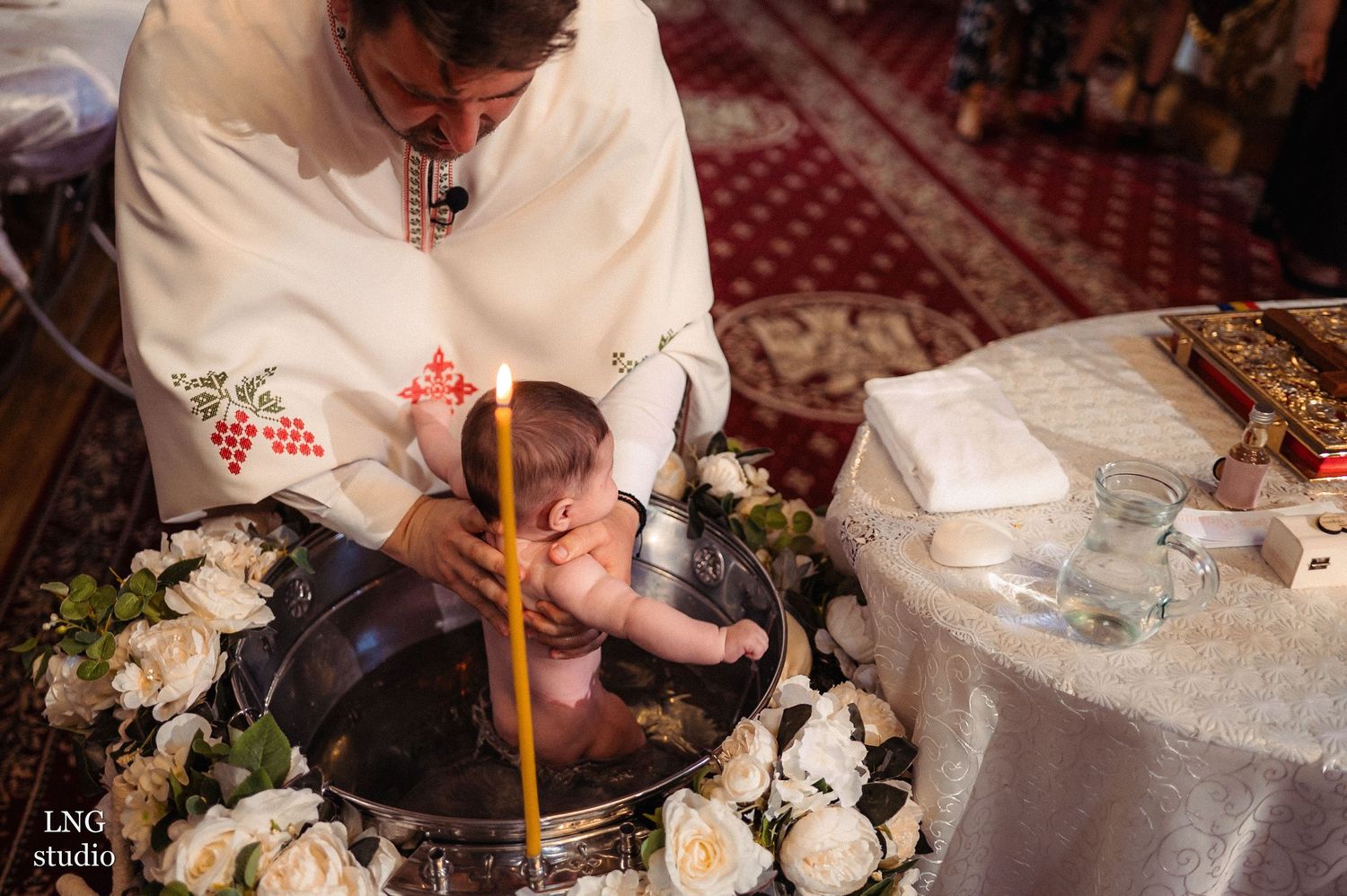 Traditional baptism ceremony with floral decorations and religious items.