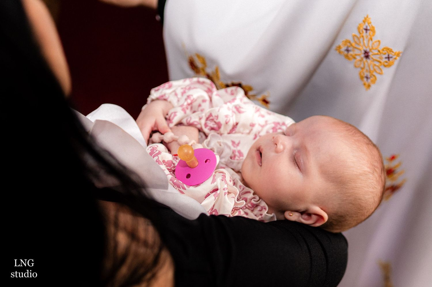 Baby in white baptismal gown during religious ceremony.