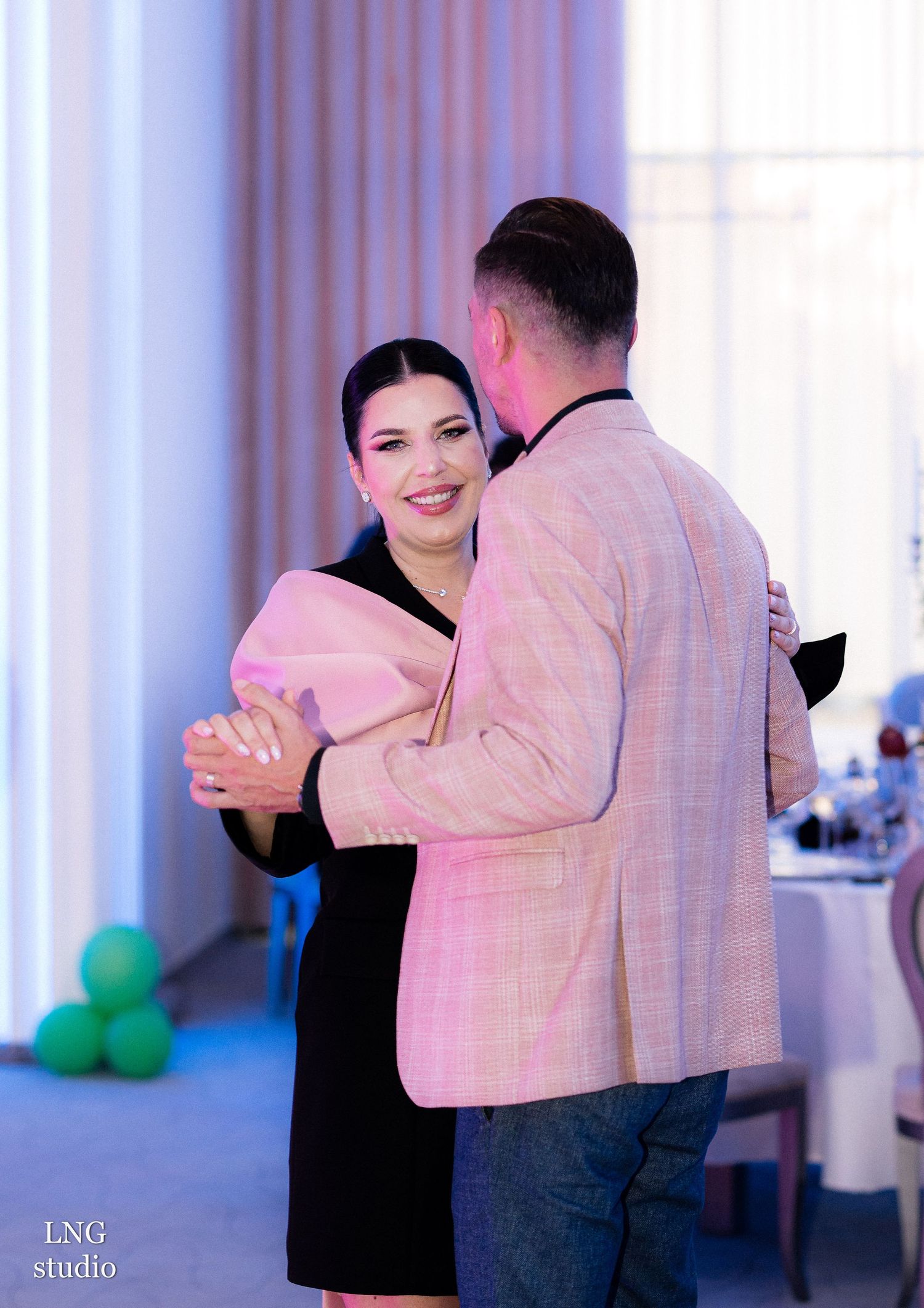 Celebration event with pink lighting and dancing in an elegant venue.