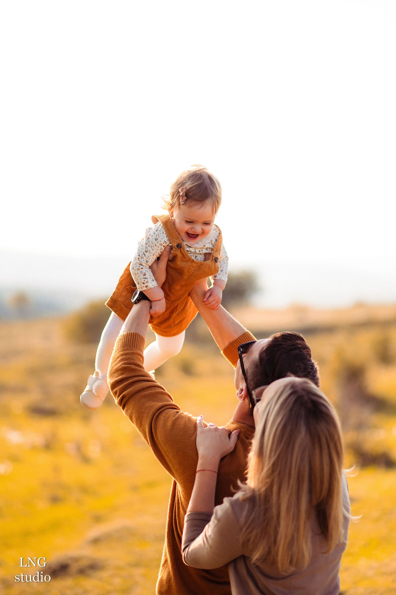 A heartwarming family moment captured during sunset in a golden field.
