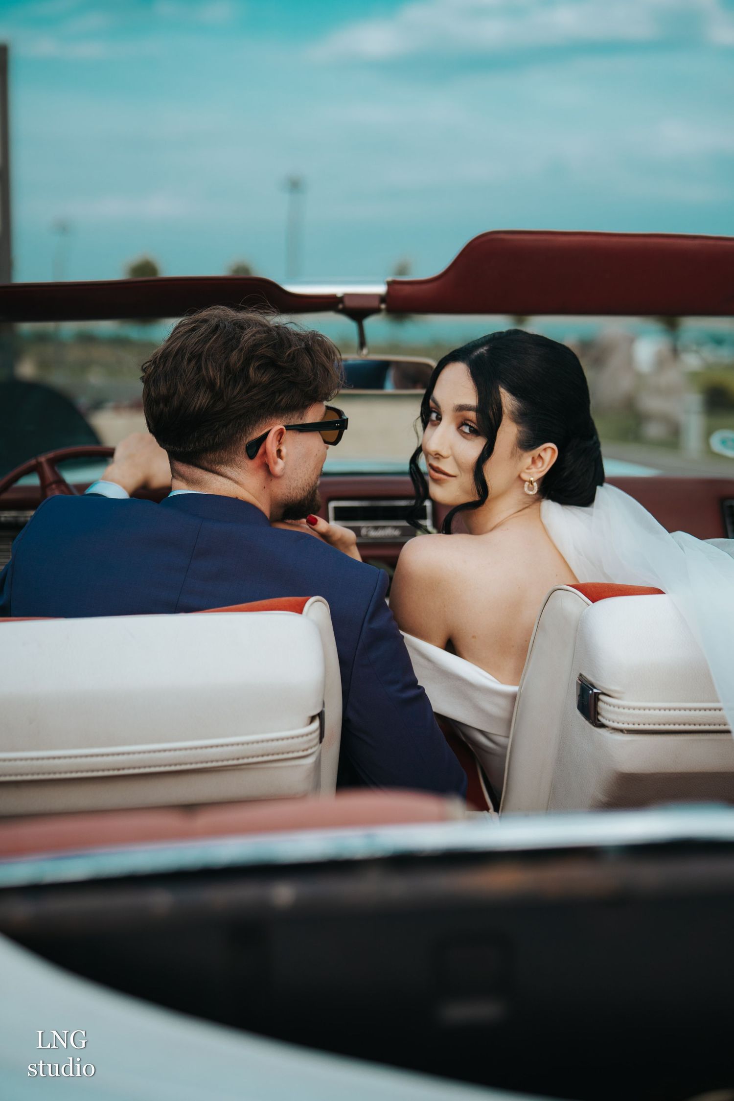 Romantic couple sharing intimate moments in a classic vintage convertible car on a sunny day.