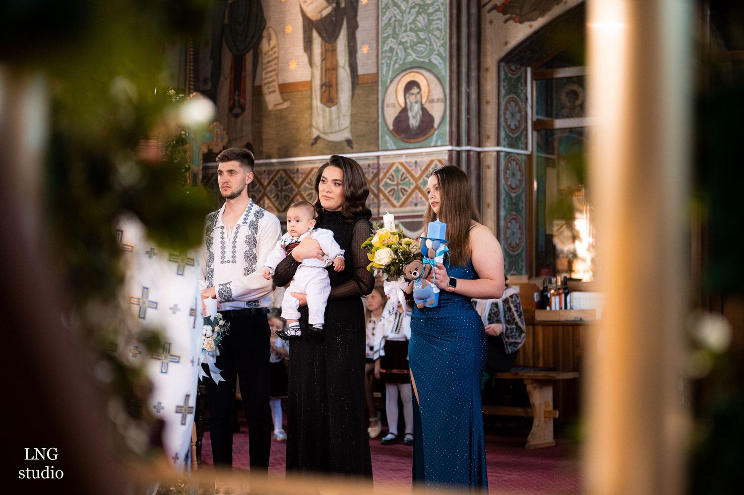 Baptismal ceremony in an ornate Orthodox church with decorative icons and candles.
