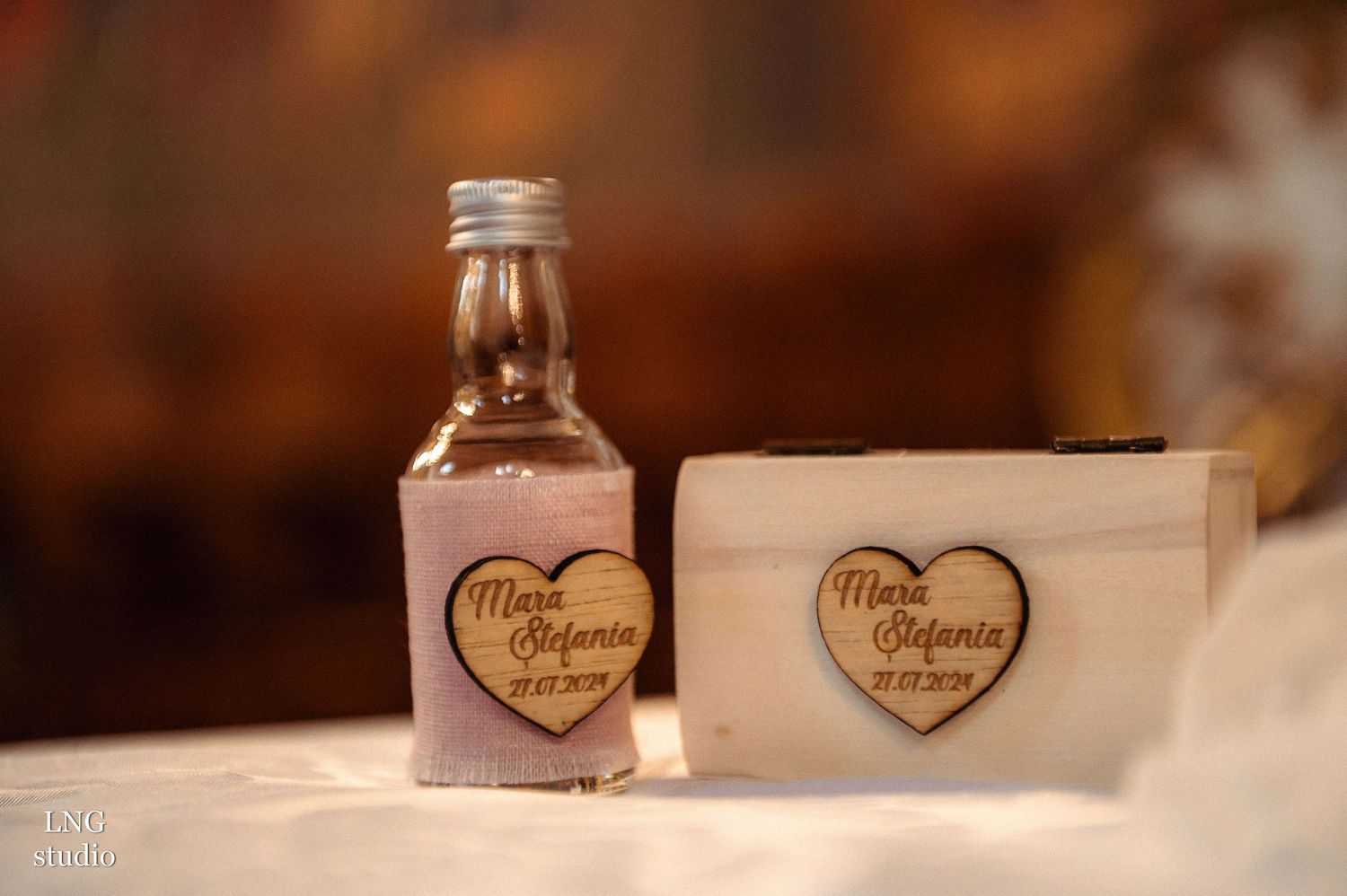 Decorative glass bottle and box with heart-shaped labels on white surface.