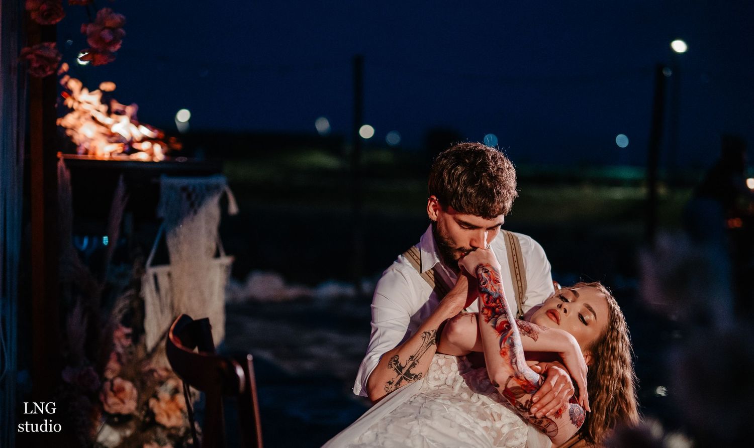 Romantic couple dancing together at night under twinkling lights during their wedding celebration.