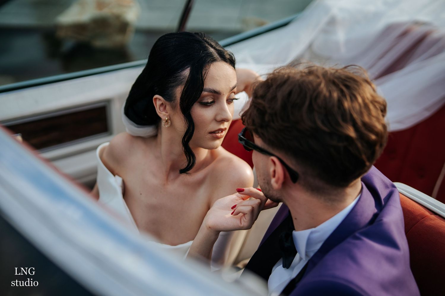 A romantic moment captured between newlyweds in a vintage car during their wedding photoshoot.