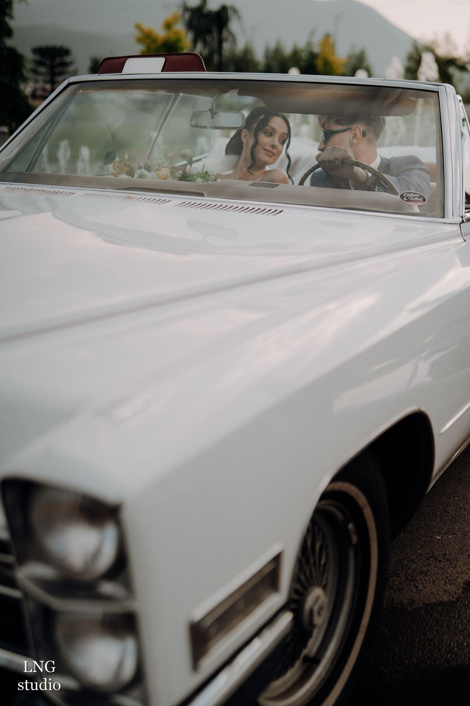 Close-up details of a pristine white classic car at an outdoor wedding setting.