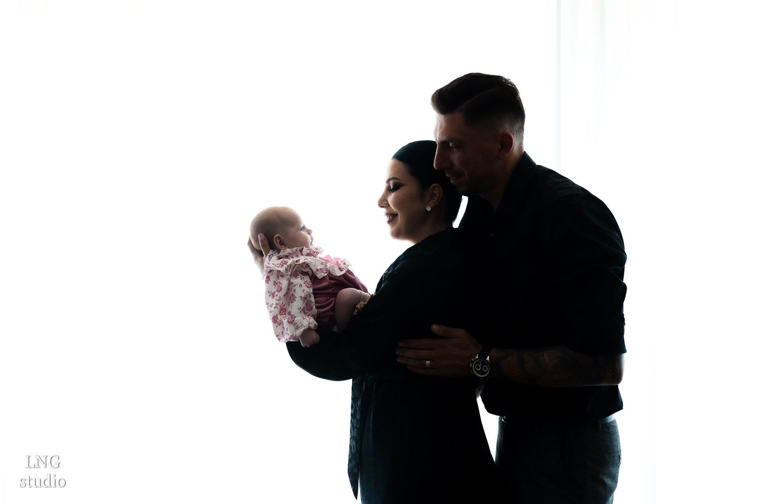 Silhouette of three figures in an intimate family moment against white background.