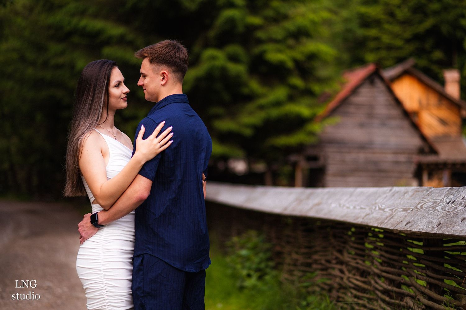 Couple in white dress and navy outfit walking together on outdoor path in summer setting.
