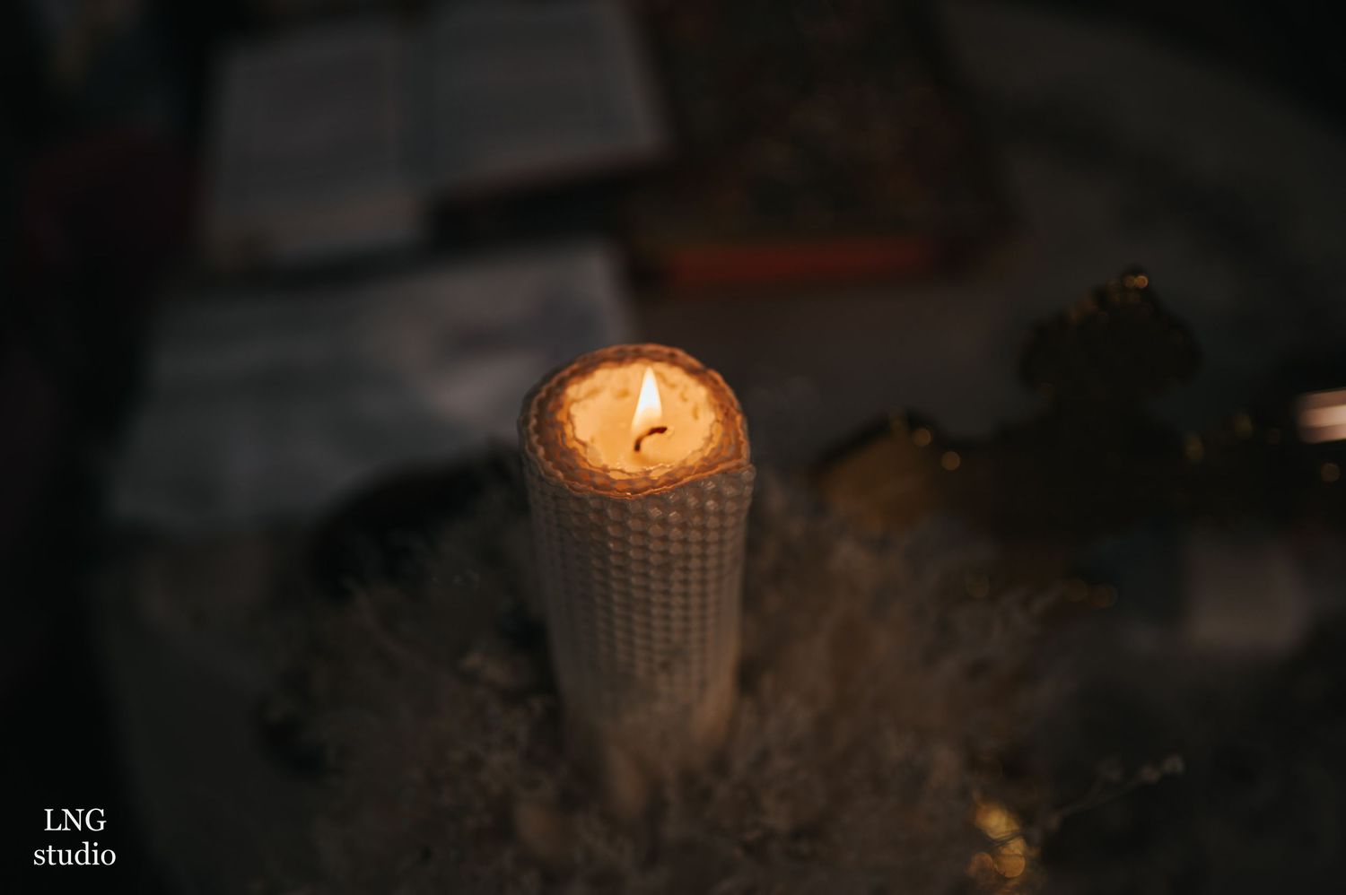 Glowing candle illuminates a dark church setting during a baptismal service.