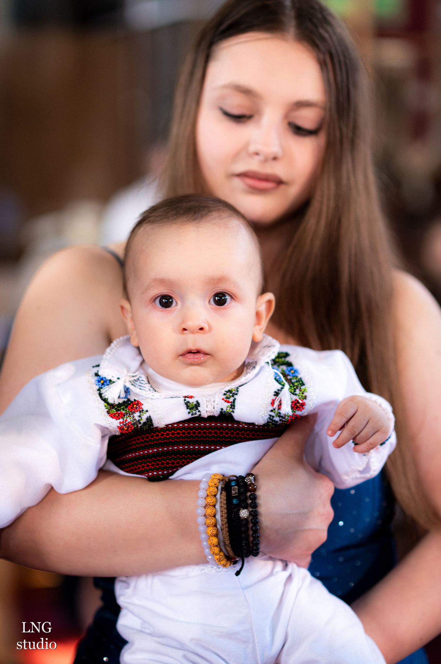 Traditional baptism ceremony with white dress and embroidered details.