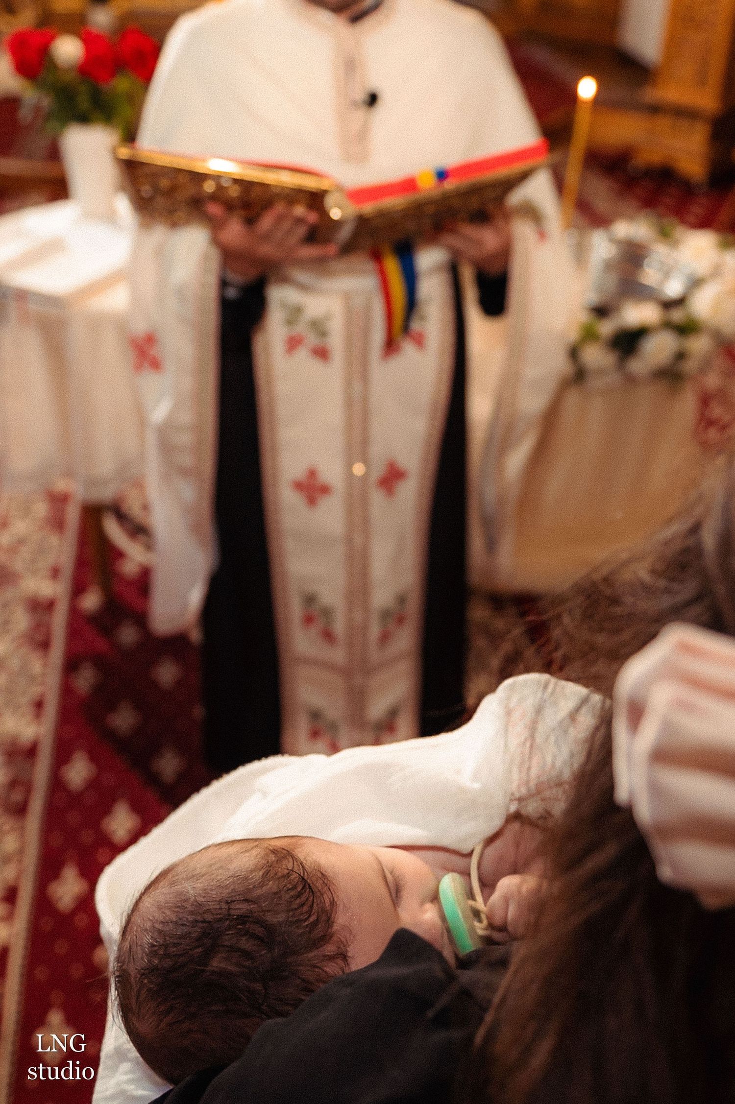 A priest reading from a religious text during a baptismal ceremony.