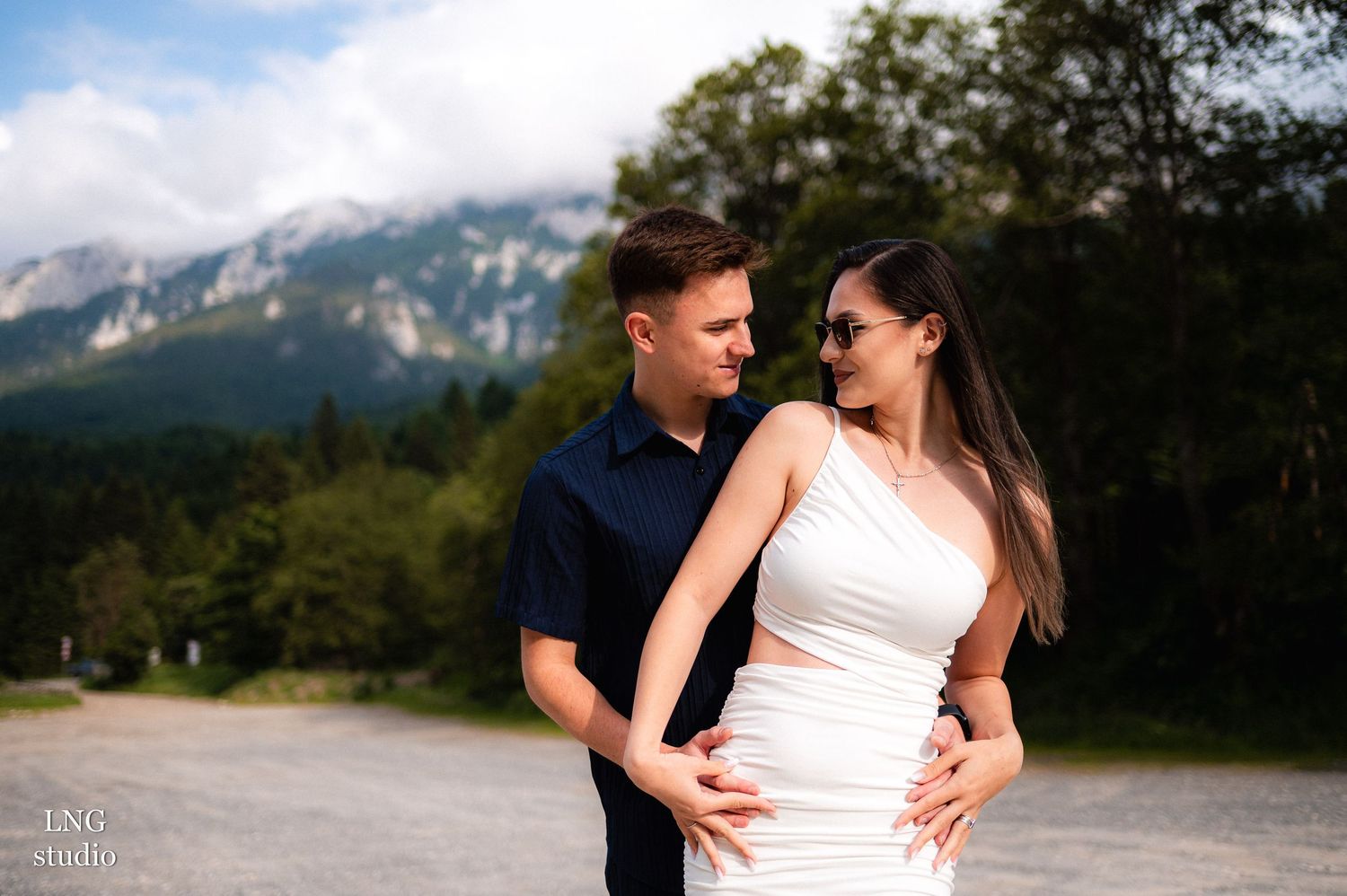 Couple shares intimate pose against dramatic mountain vista.