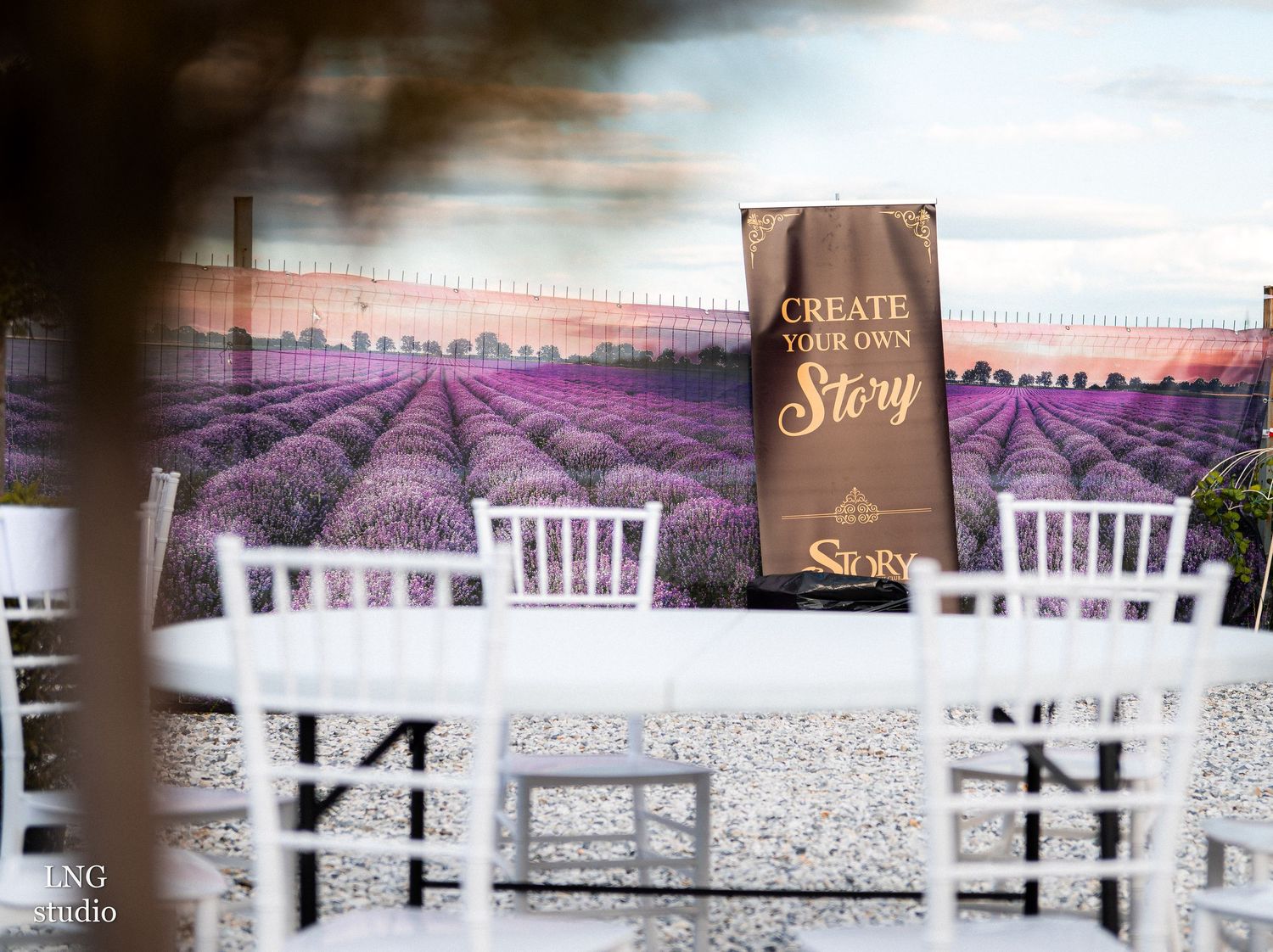Wedding reception table setup with white chairs against a purple lavender field backdrop at sunset.